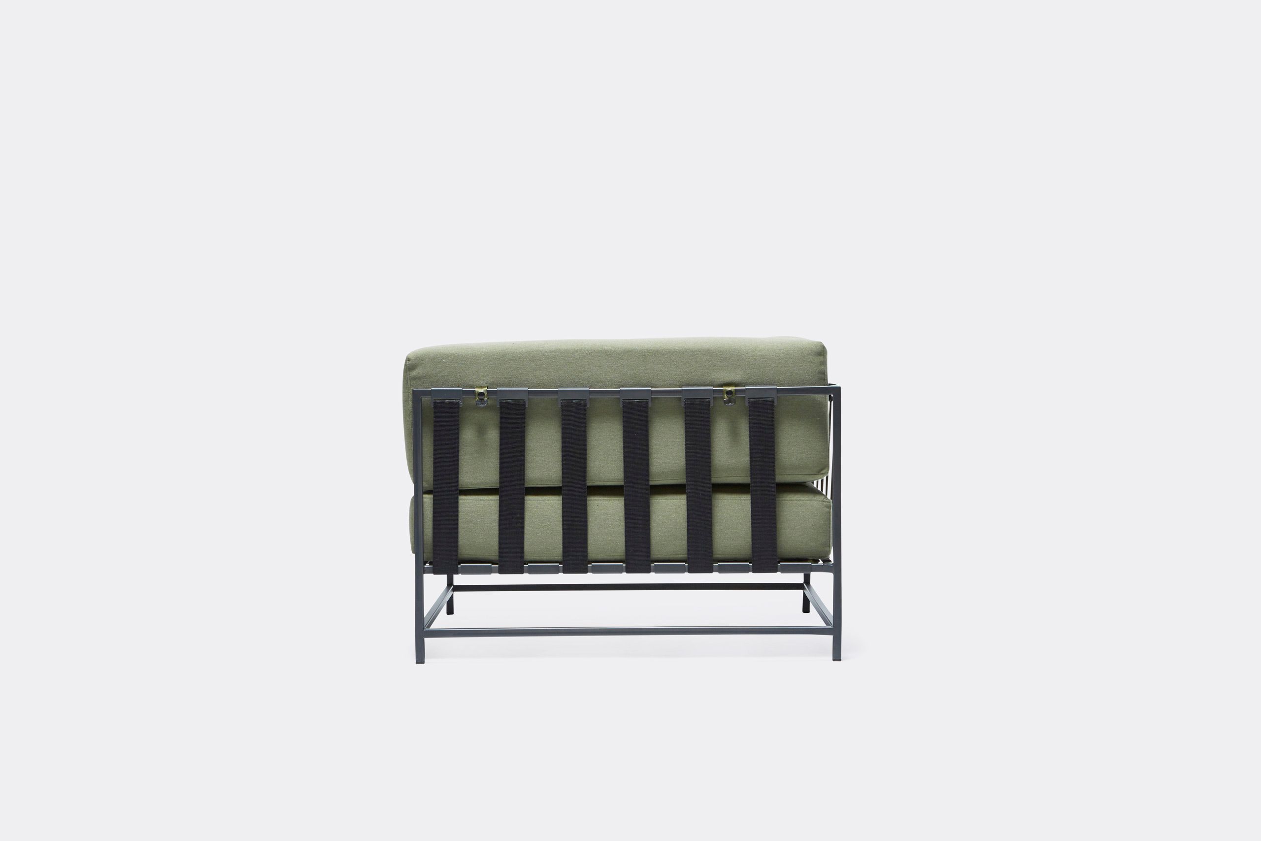 An outdoor chair with steel frame in black finish and green cushions and supporting belts
