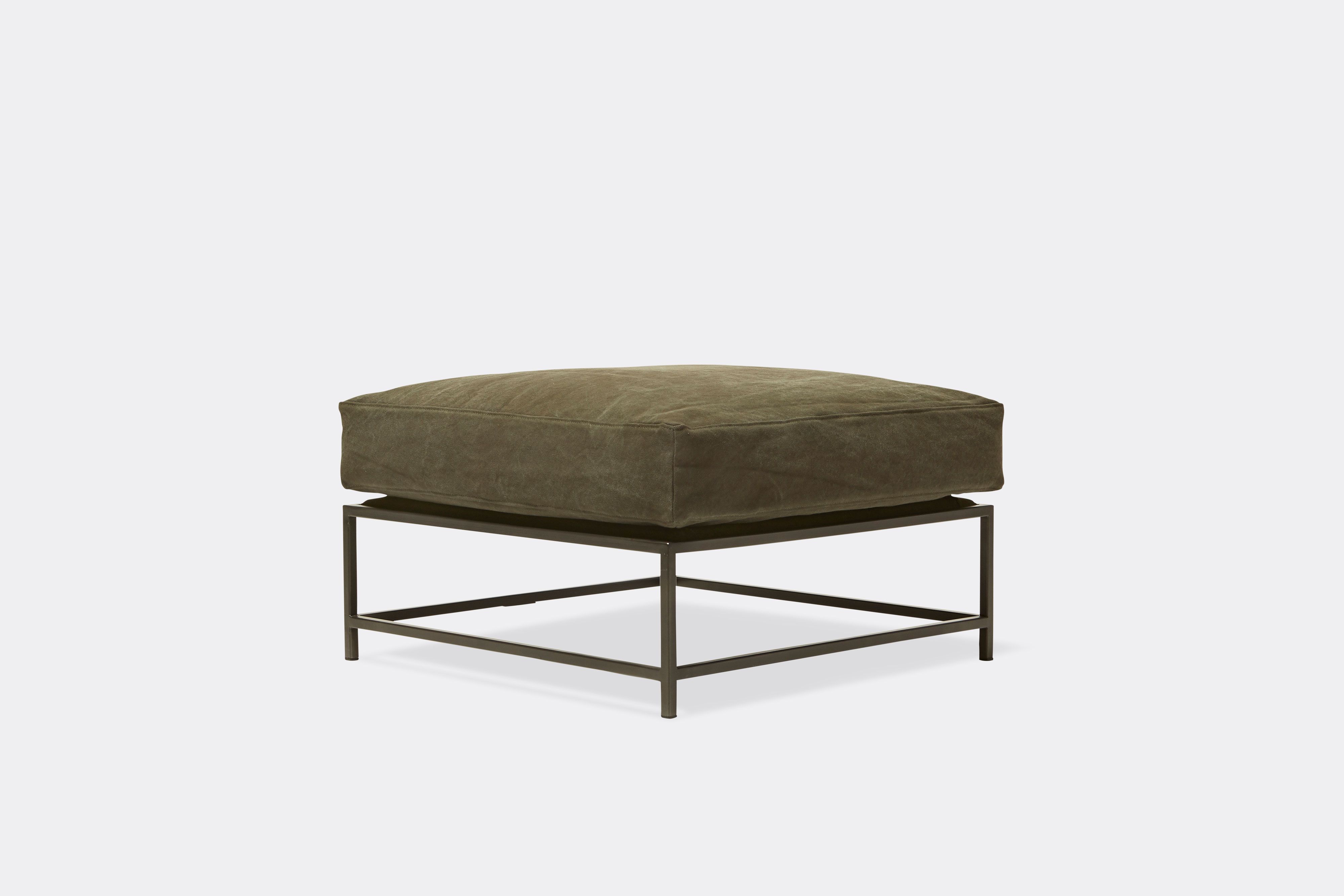 side view of green canvas ottoman with blackened steel frame