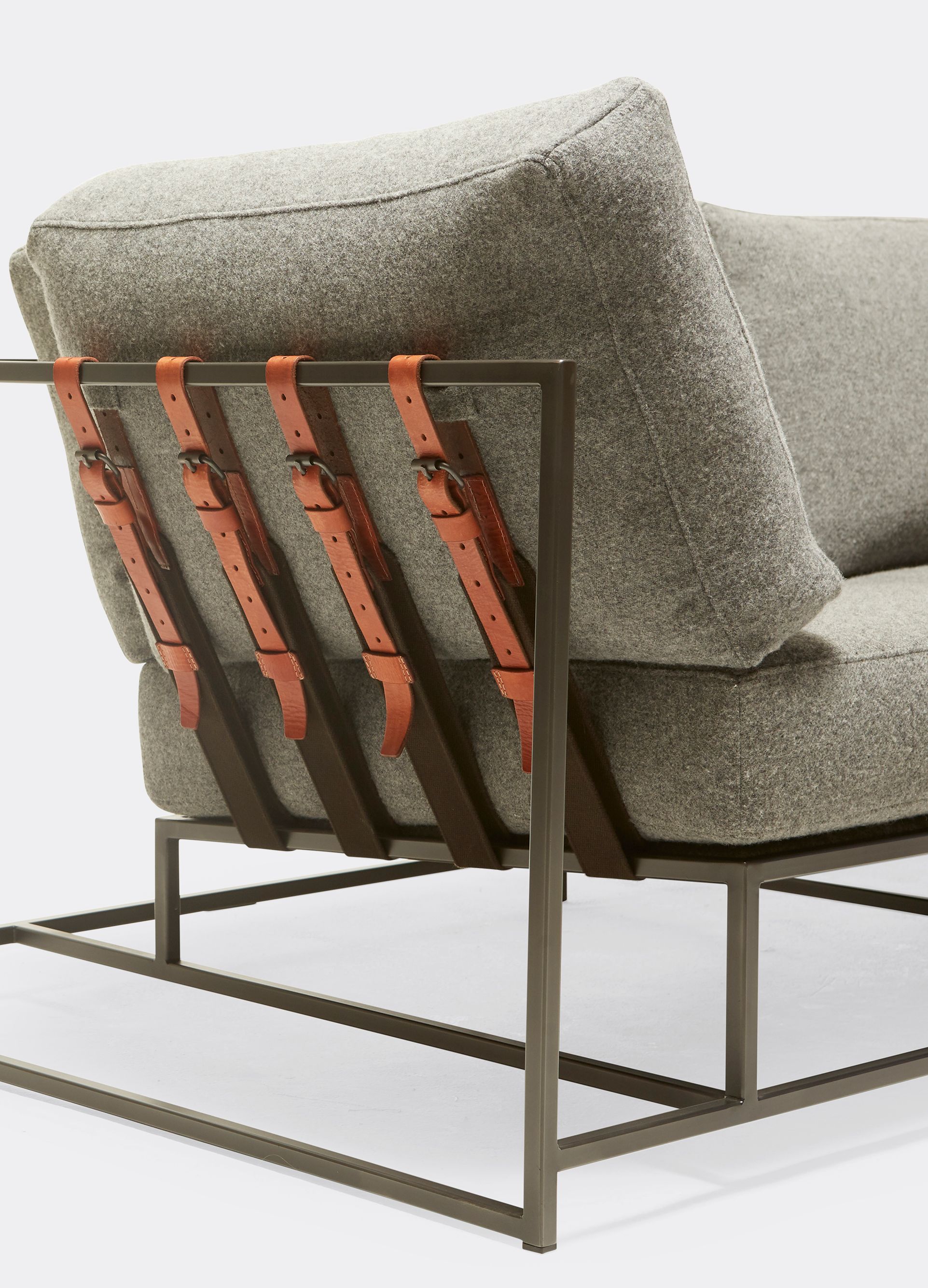  a grey wool sofa with leather straps and a steel frame