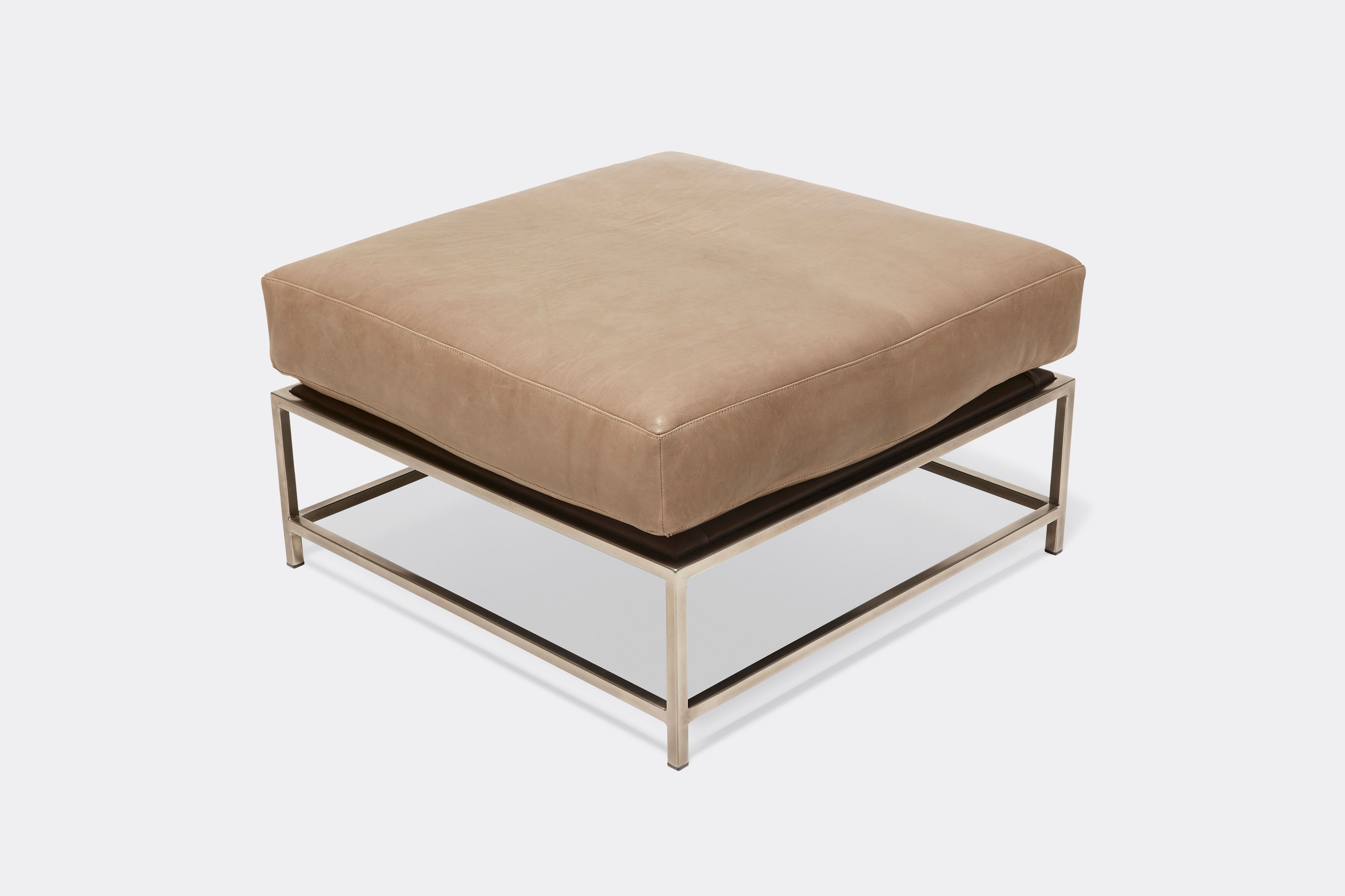 overhead of ottoman with tan leather upholstery on antique nickel metal frame