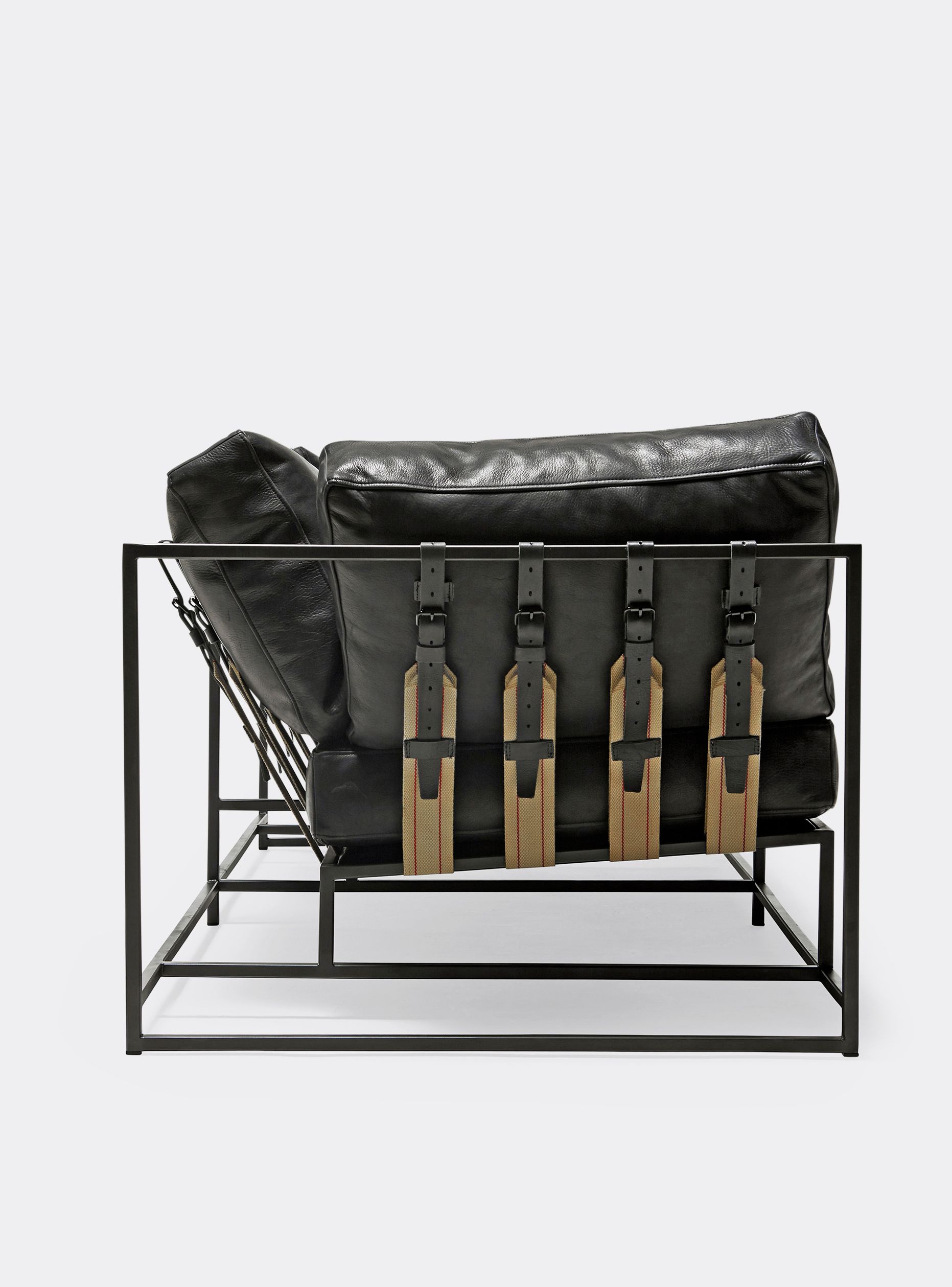 a black leather sofa with leather and webbing belts on a steel frame and shown on a white background .