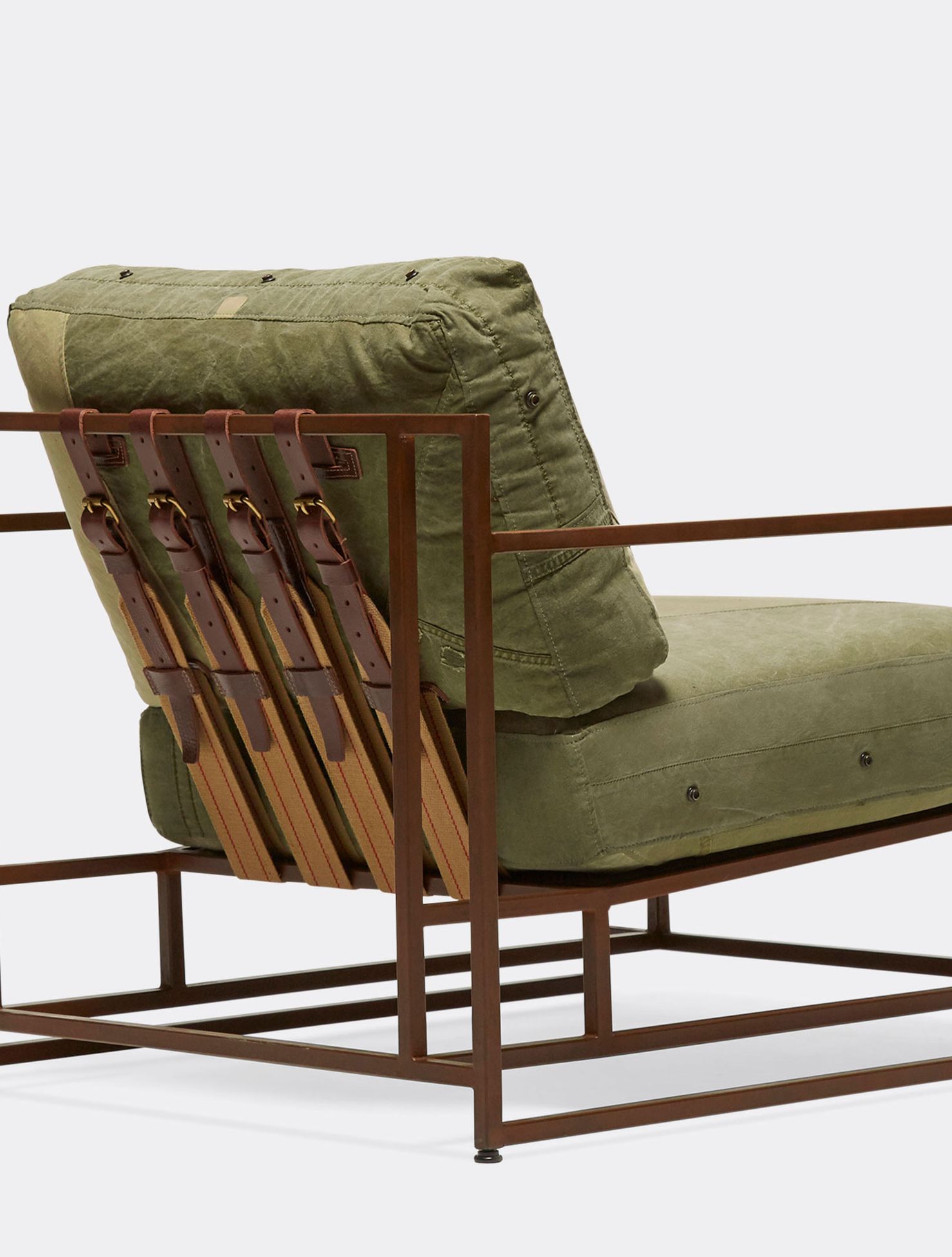 a steel framed chair with a green cushion and supporting belts on a white background .