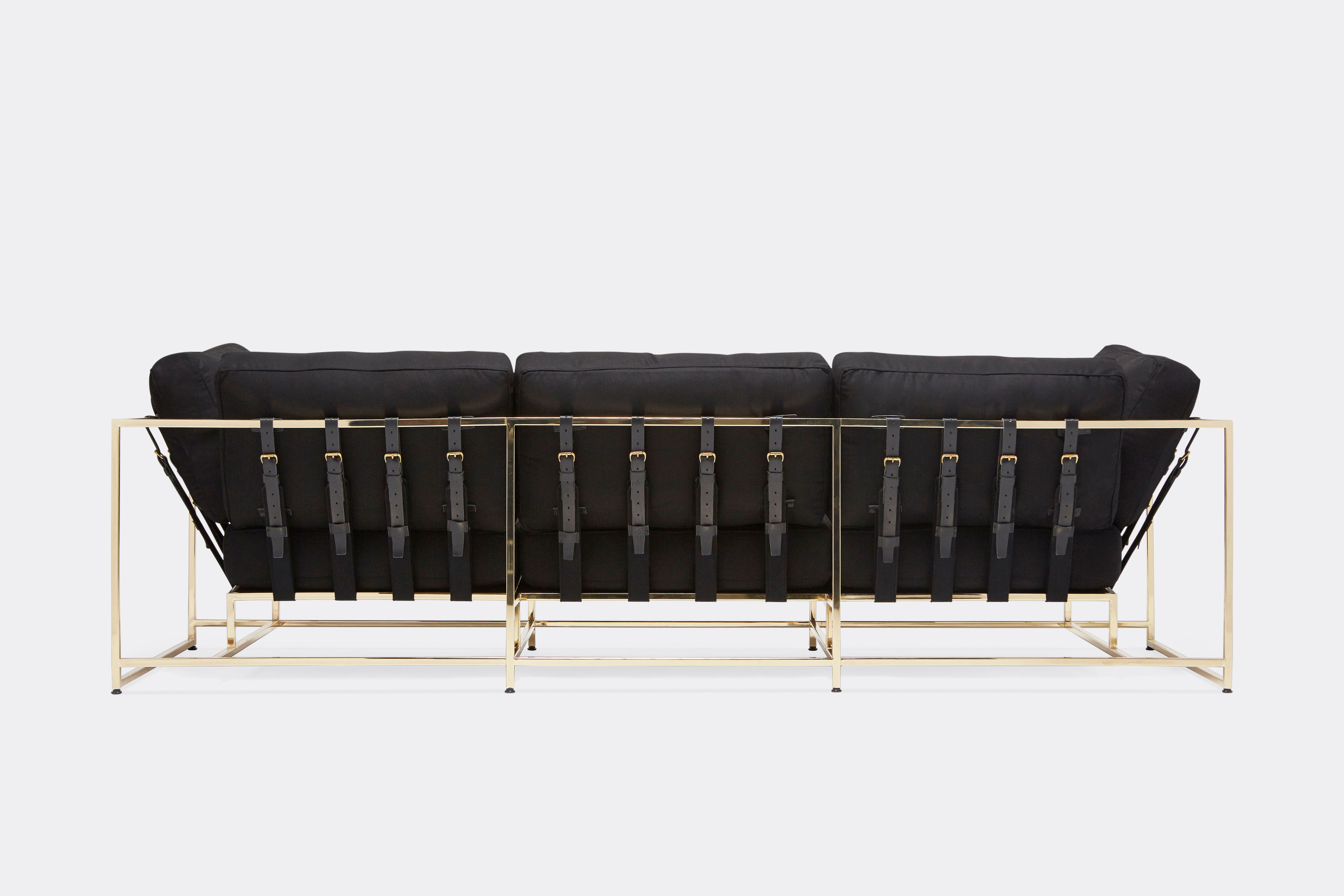 detail sideview of Sofa with black wool upholstery and black leather belts on polished brass metal frame