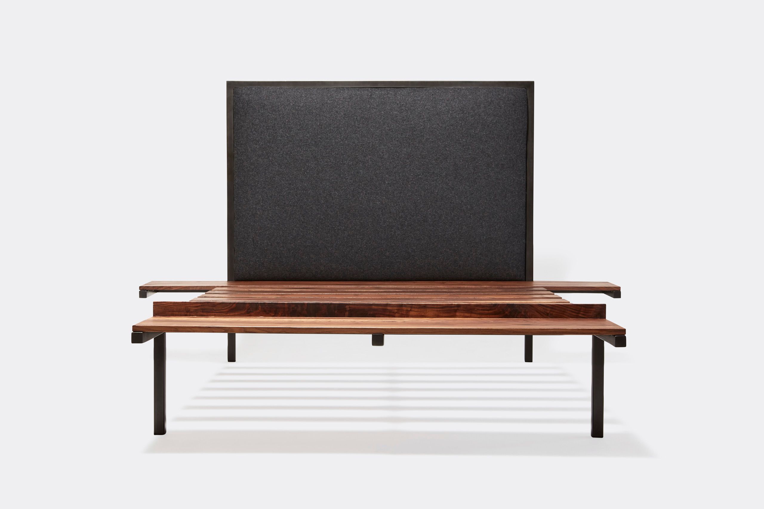 a steel frame and walnut wood bed with a black wool upholstered headboard shown on a white background .