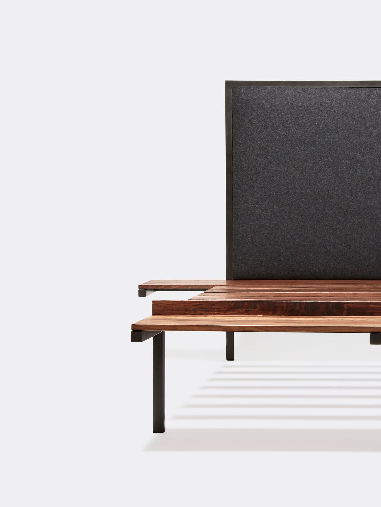 a steel frame and walnut wood bed with a black wool upholstered headboard shown on a white background .