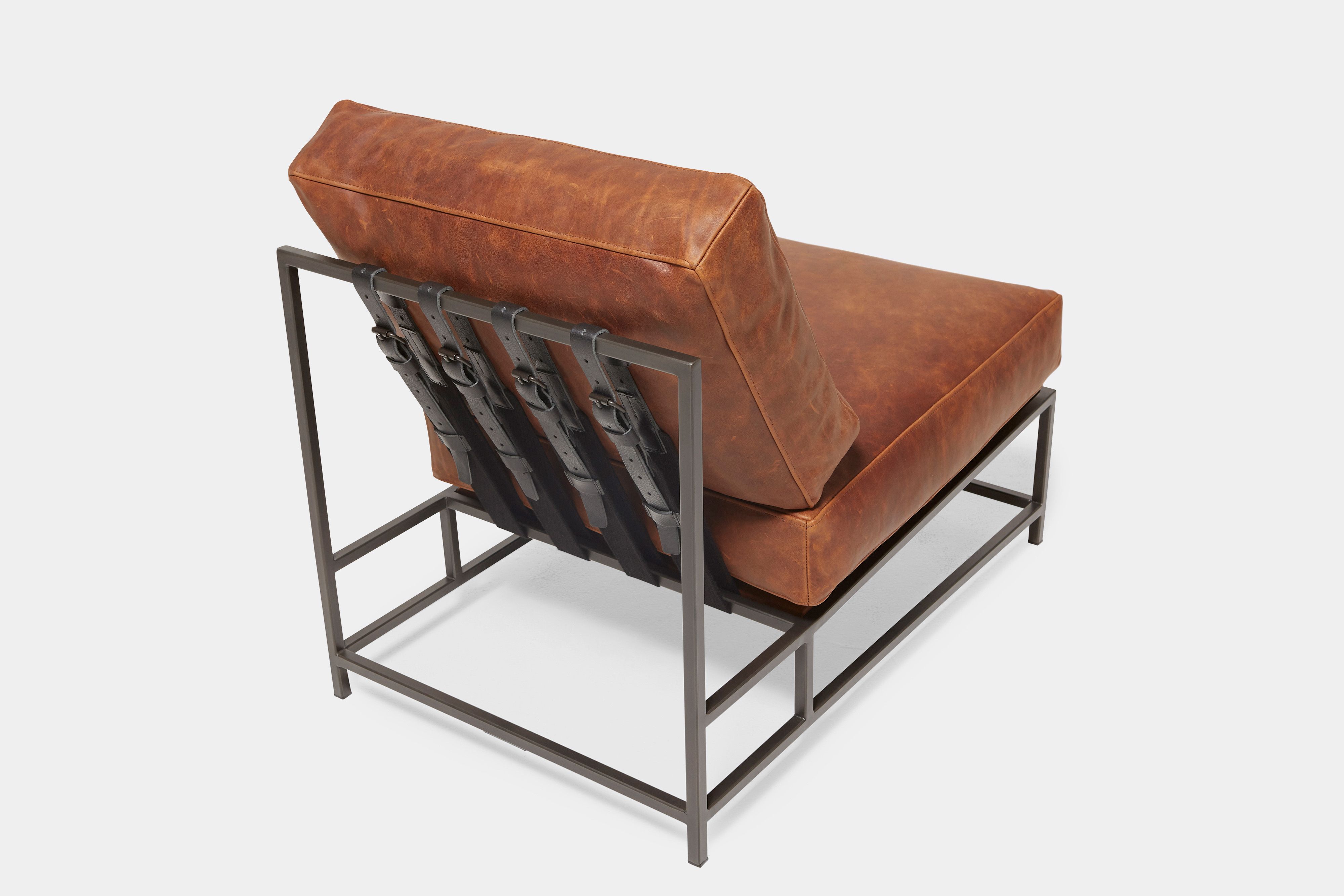 overhead view of lounge chair with brown leather upholstery and black leather belts on black metal frame
