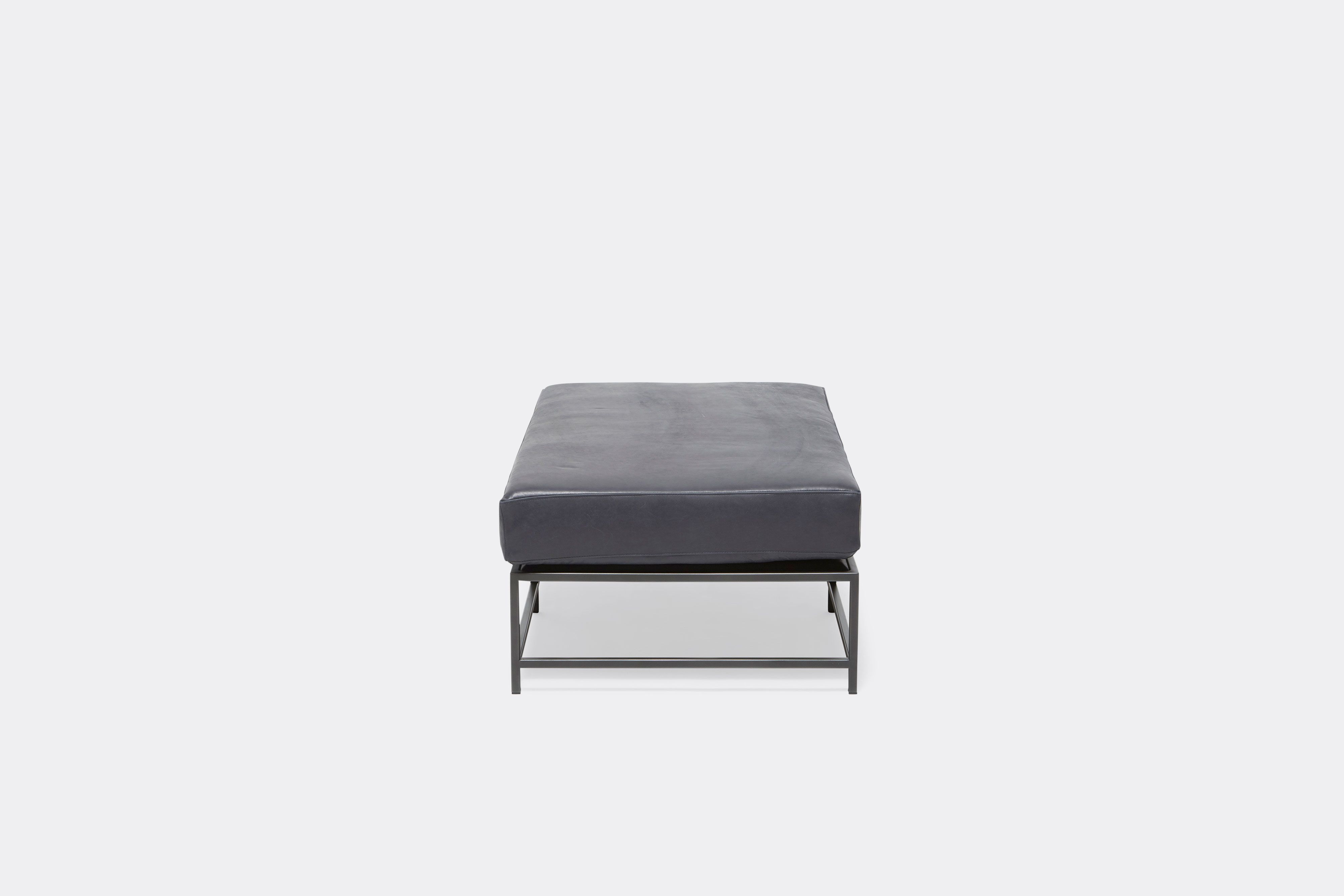 side of bench with blue leather upholstery on black metal frame