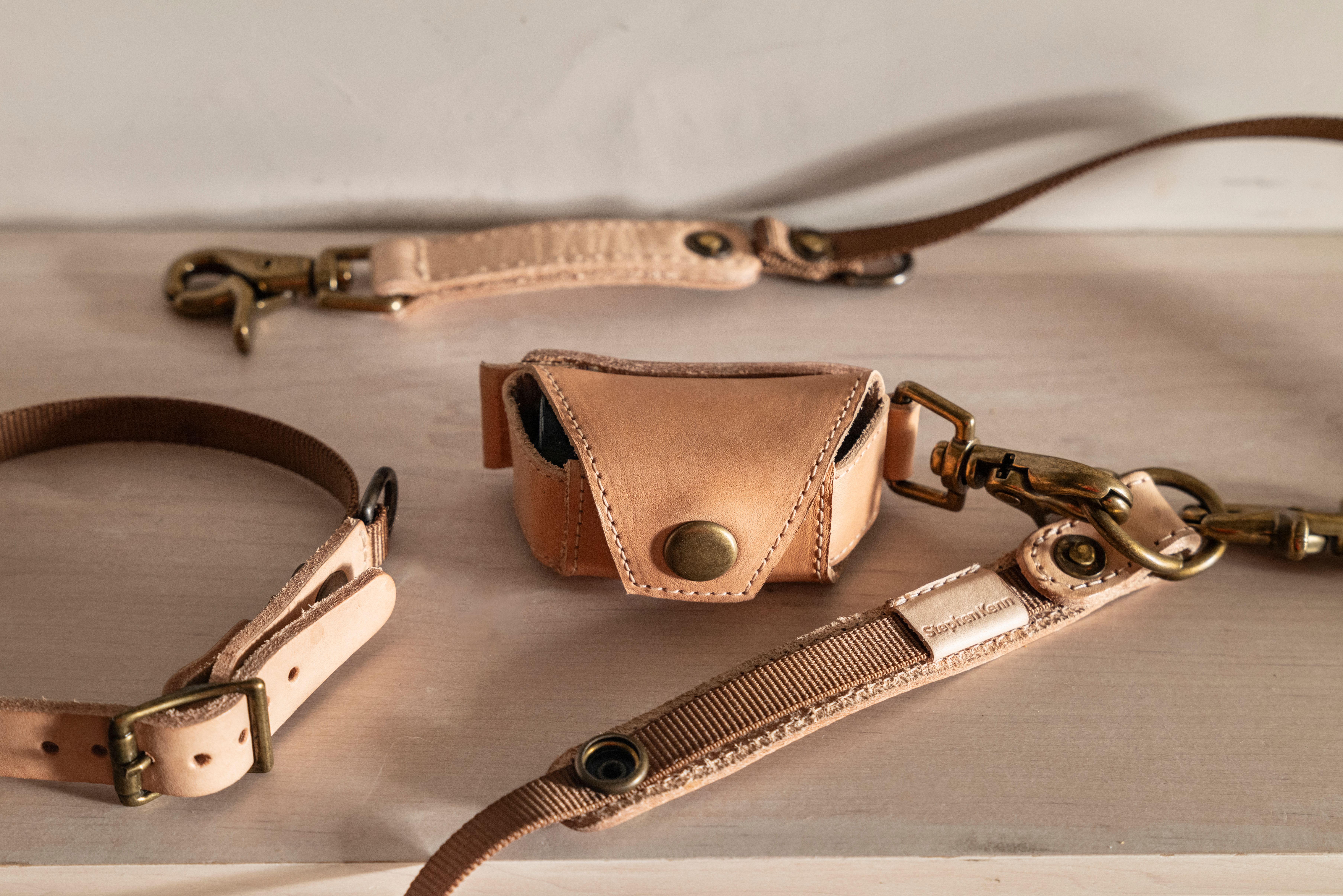 Natural leather dog collar, leash, and small pouch with brass hardware.
