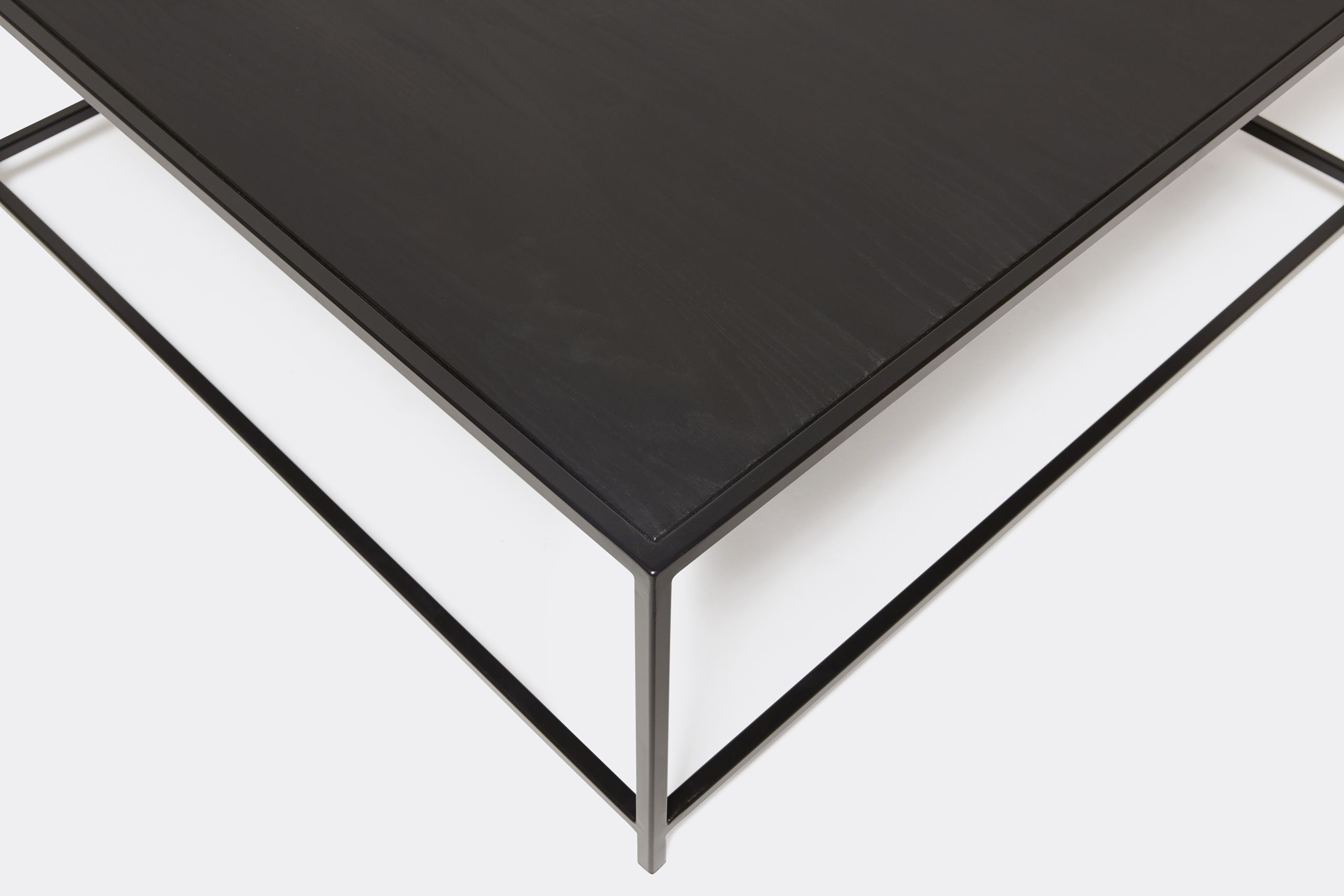 a black wood topped coffee table with a metal frame on a white background .