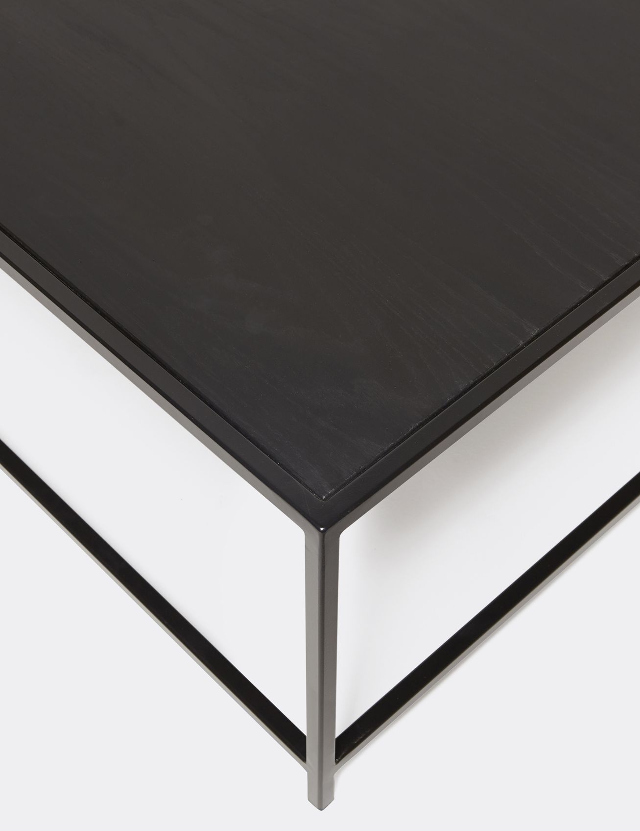 a black wood topped coffee table with a metal frame on a white background .