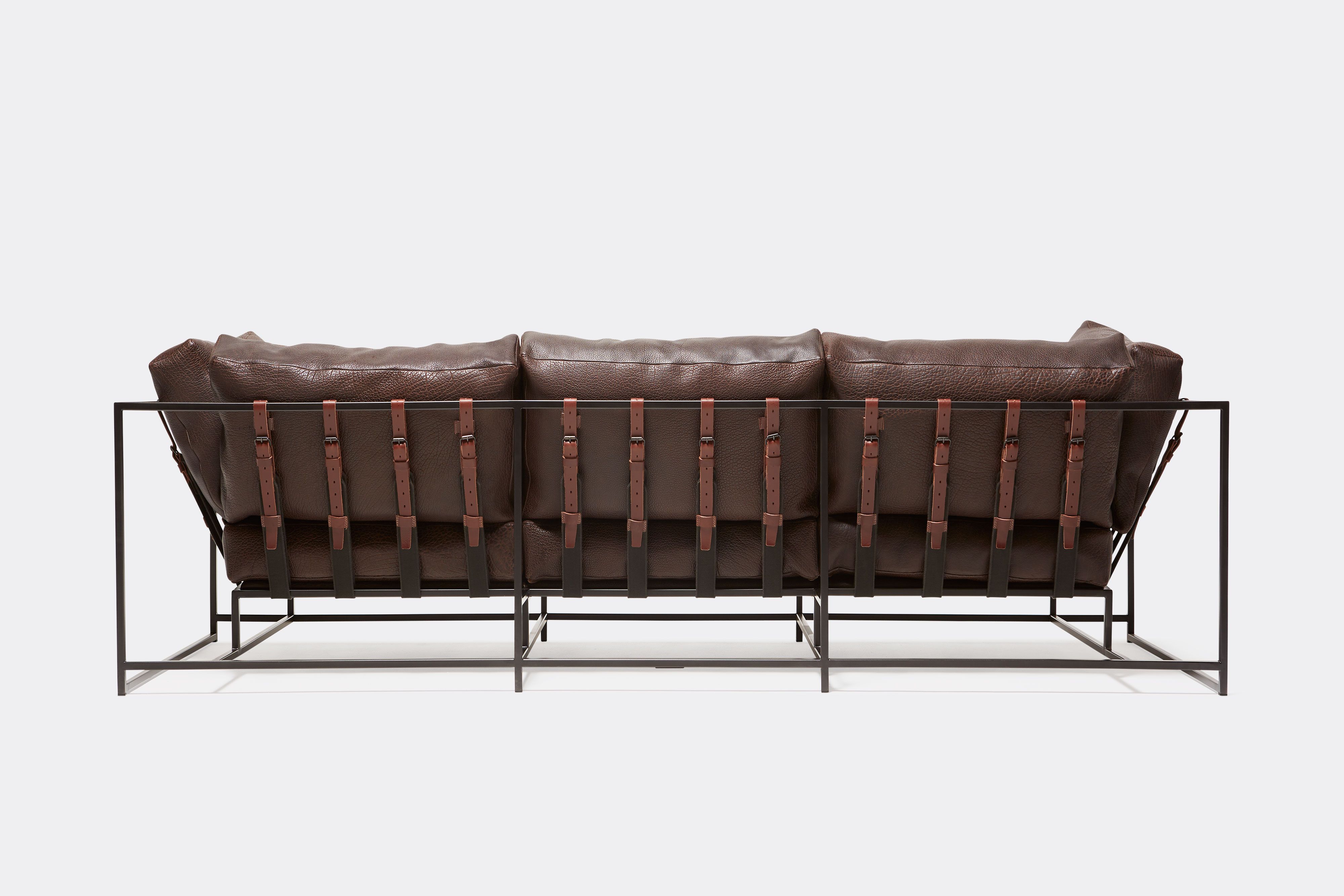 Back view of brown leather sofa with blacken steel metal frame and leather belts.