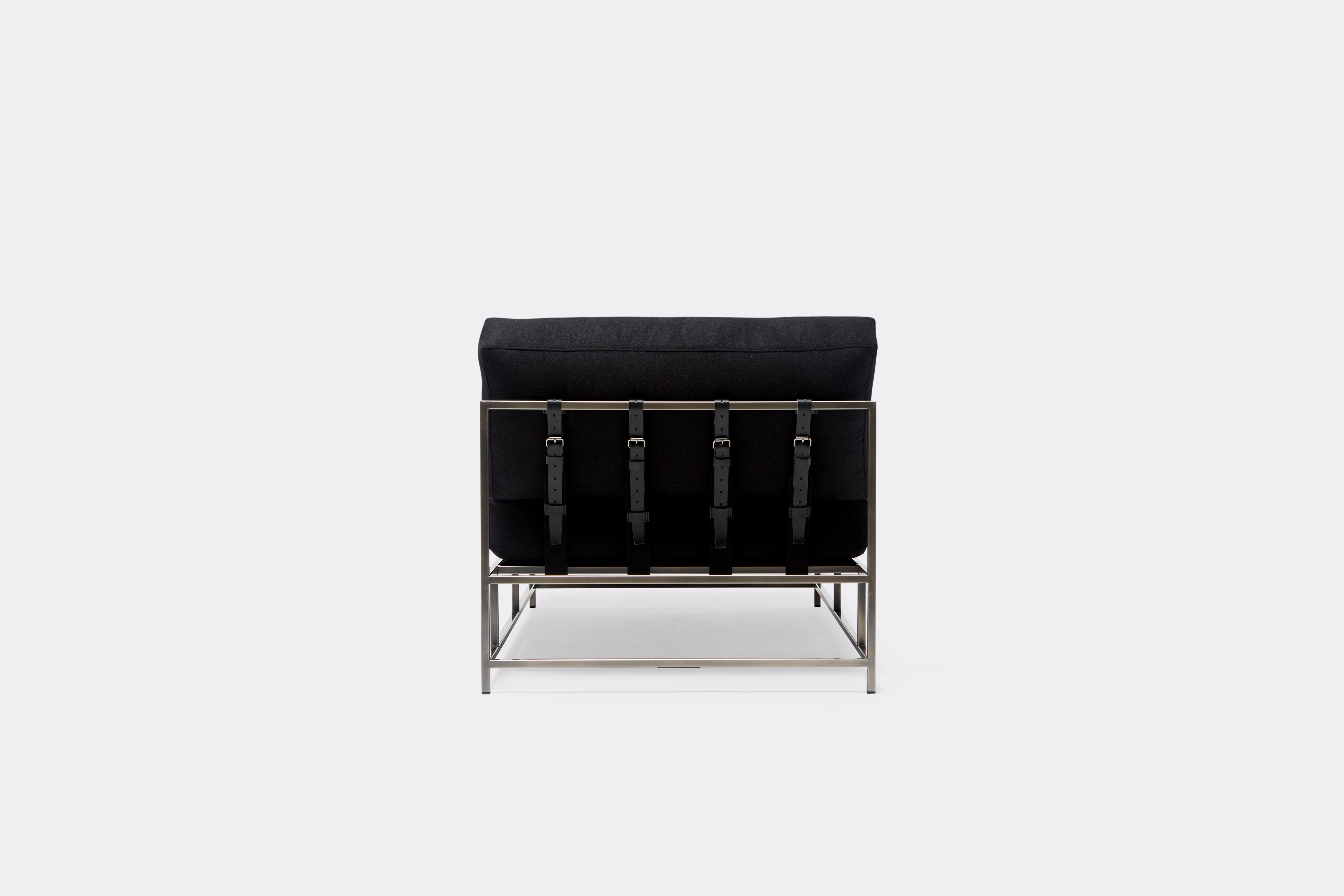 back of chaise lounge with black wool upholstery and black leather belts on antique nickel metal frame
