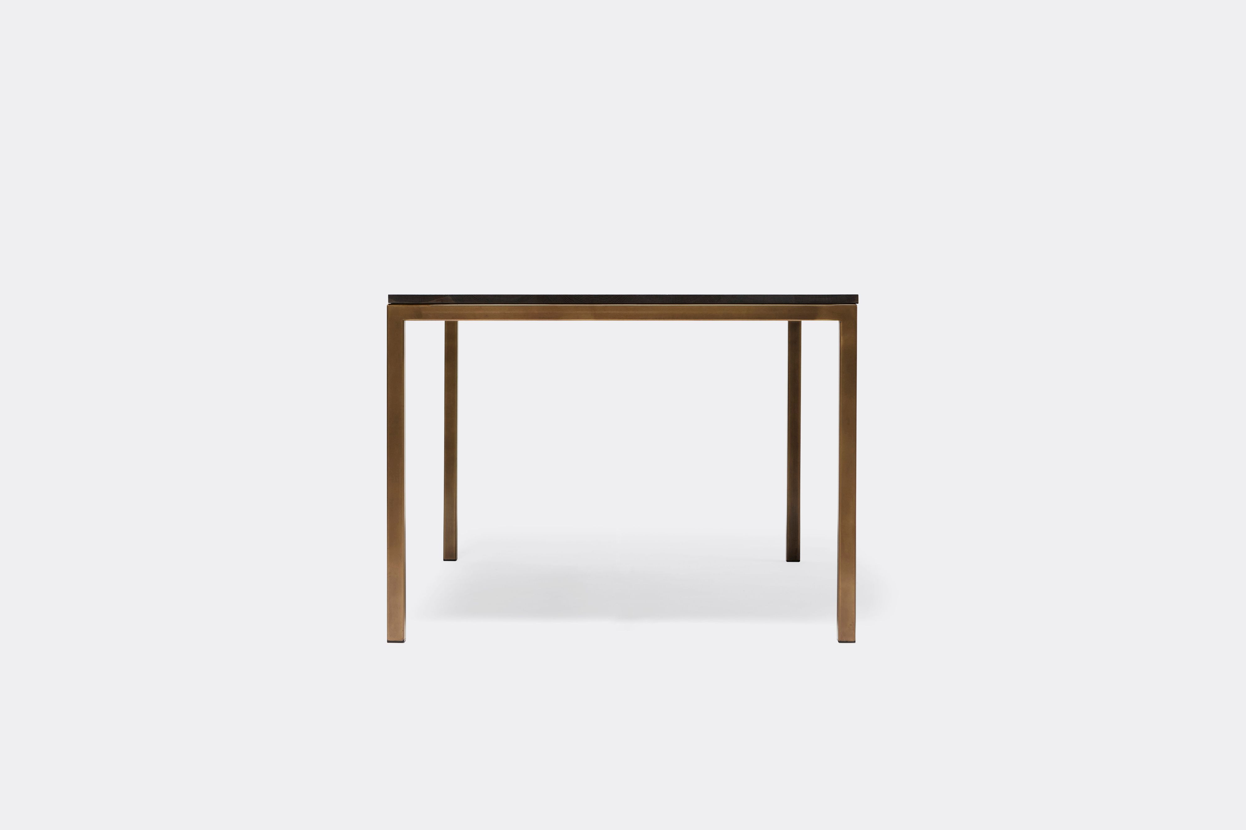 Front view of dining table with ebonized oak wood top and antique brass metal legs
