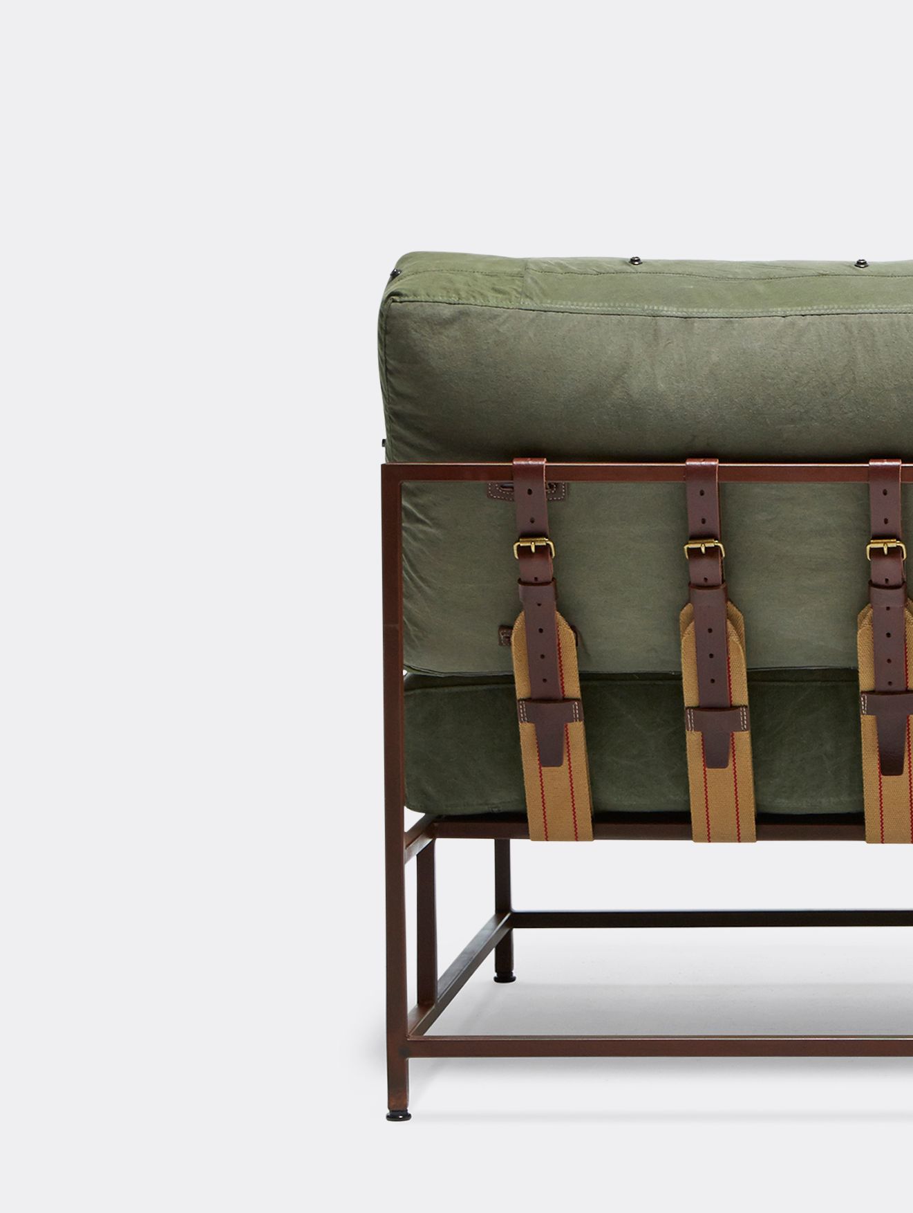 a steel framed loveseat sofa with green canvas cushions and leather and webbing supporting belts shown on a white background .