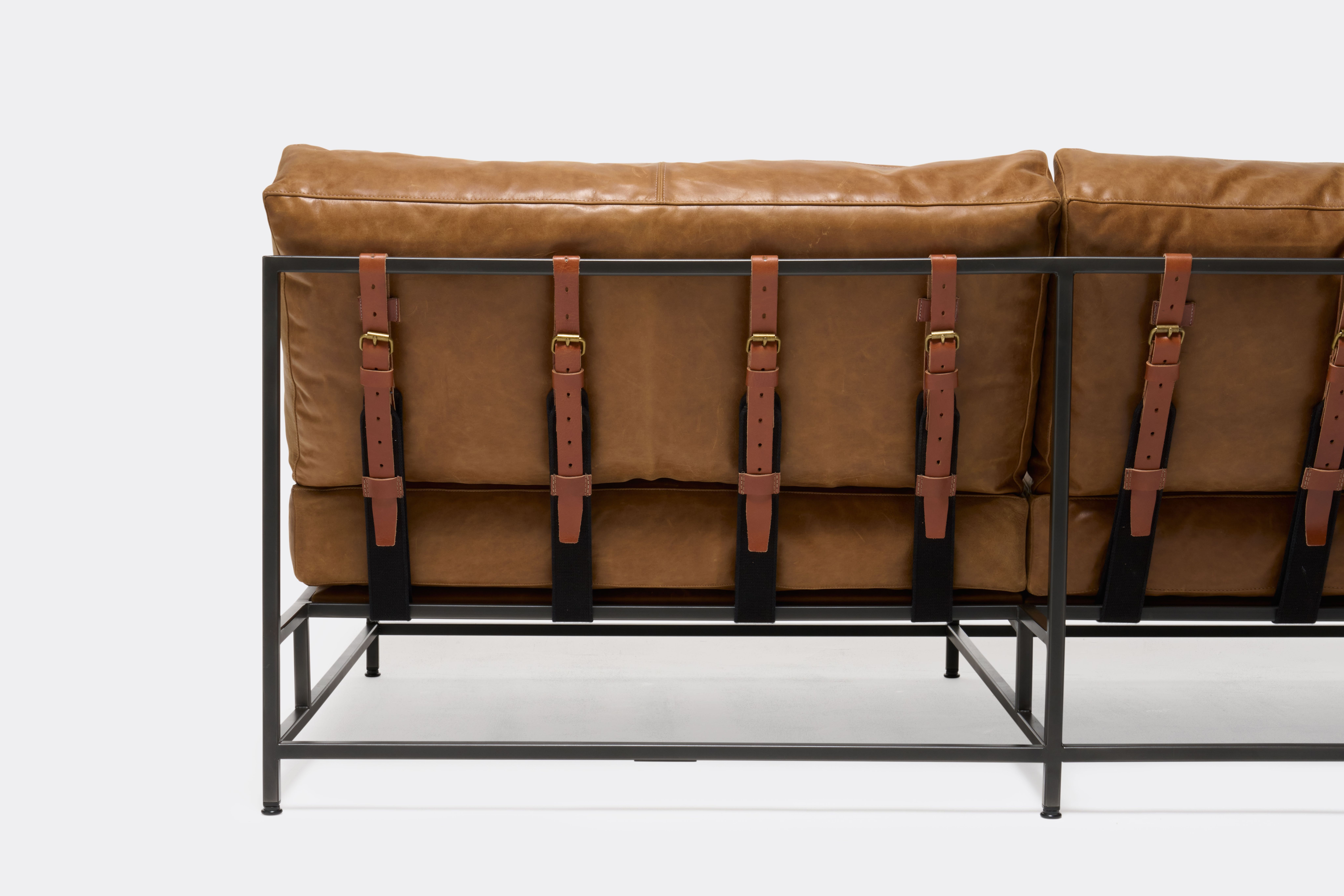 back of loveseat with brown leather upholstery and brown leather belts on black metal frame