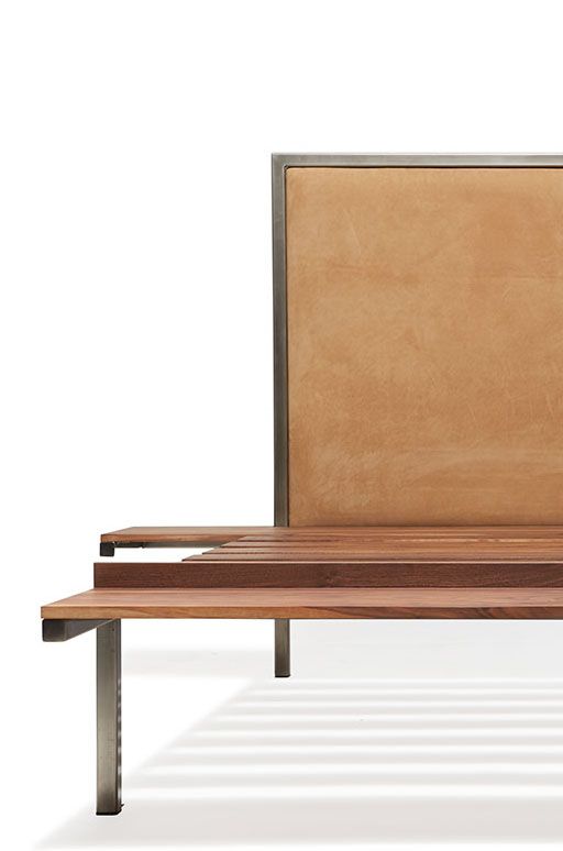 a steel and walnut wood bed with a brown leather headboard on a white background