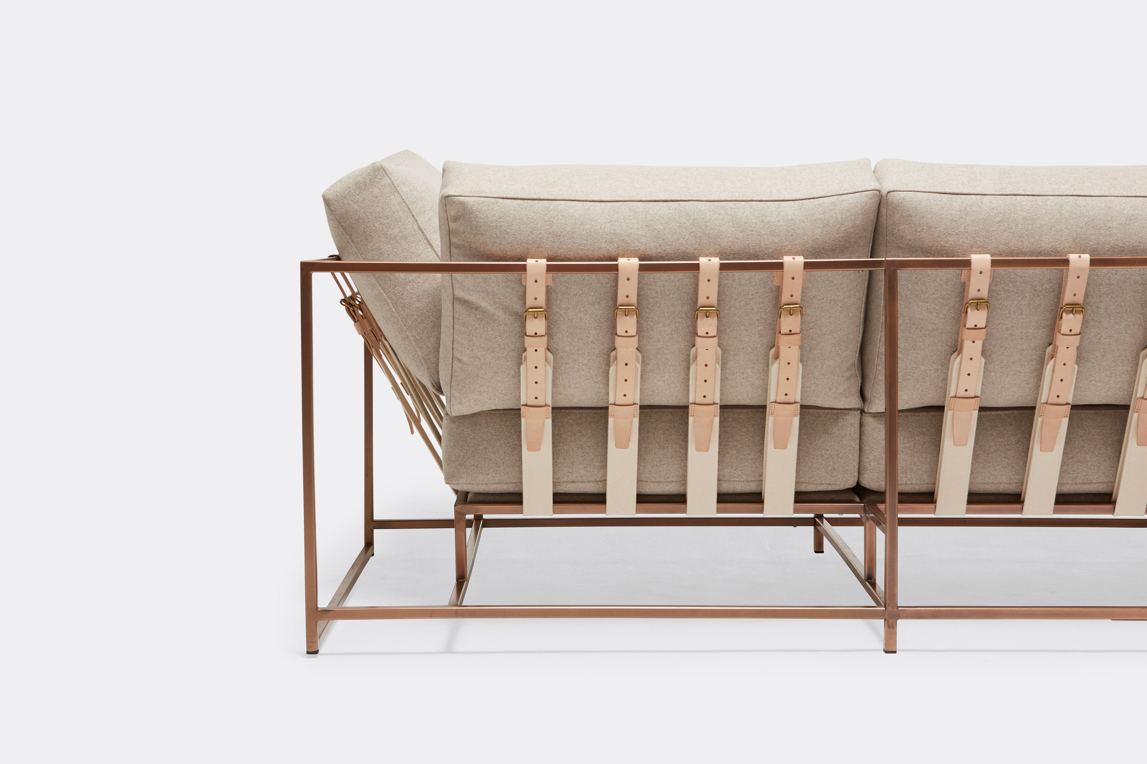 back of three piece sofa with cream wool upholstery and natural tan leather belts on antique copper metal frame