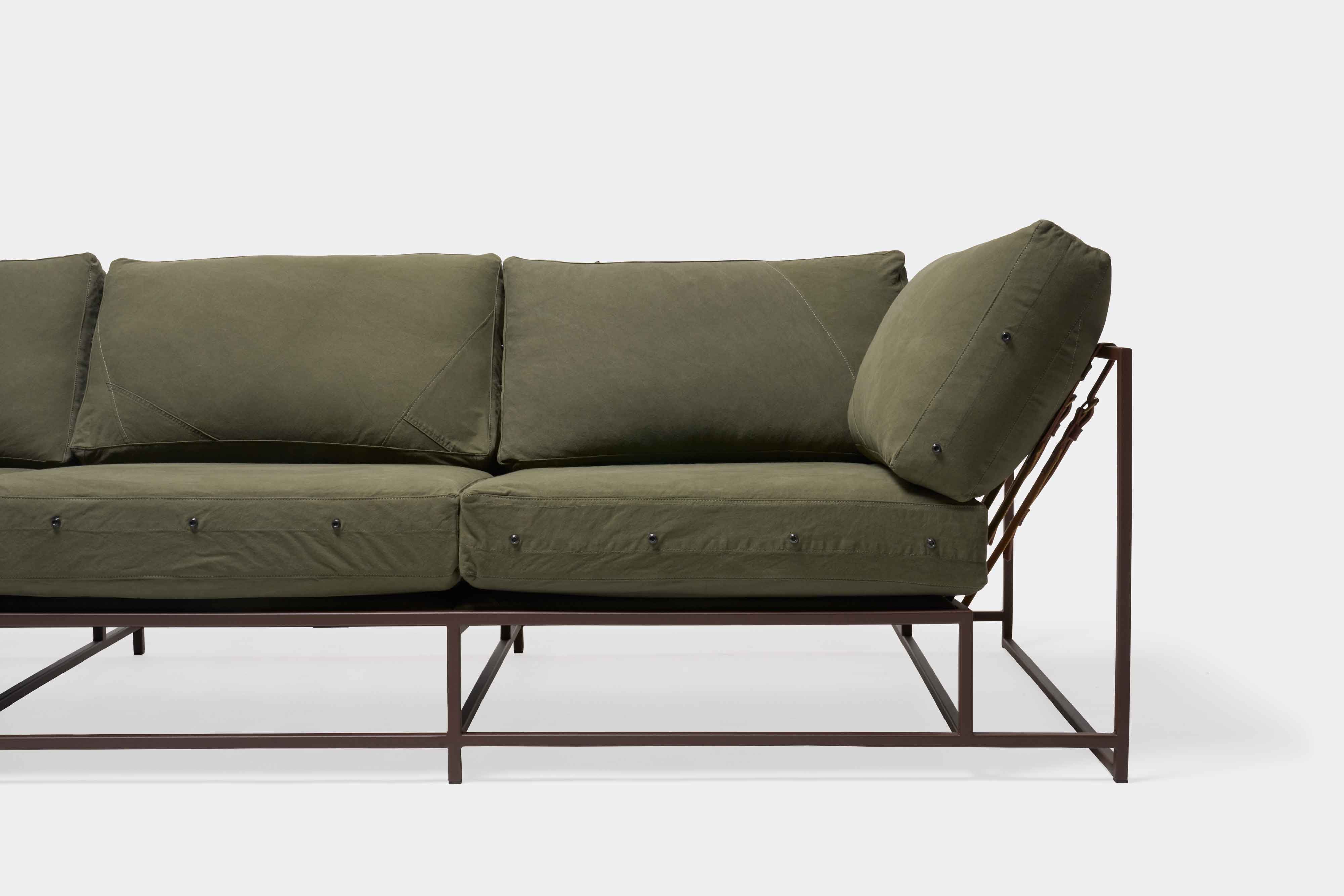 a green couch with a metal frame and leather straps