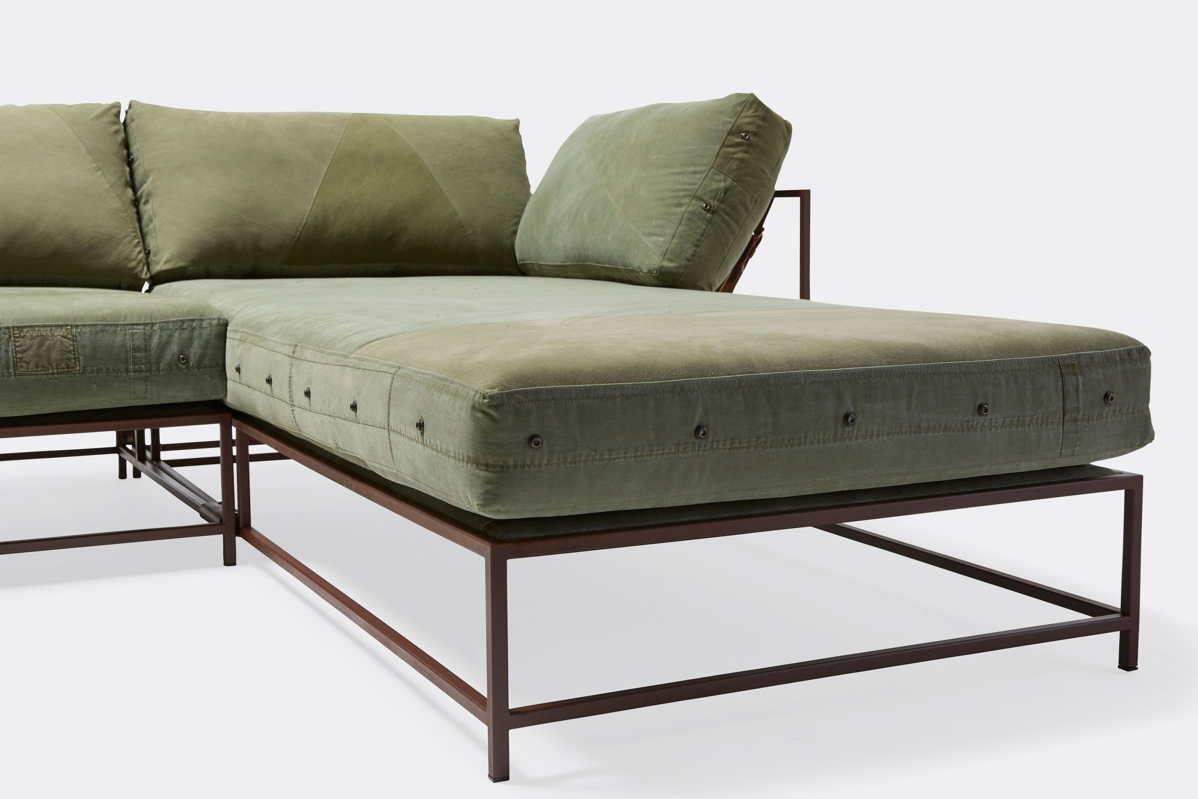 side of sectional with green canvas upholstery on marble rust metal frame