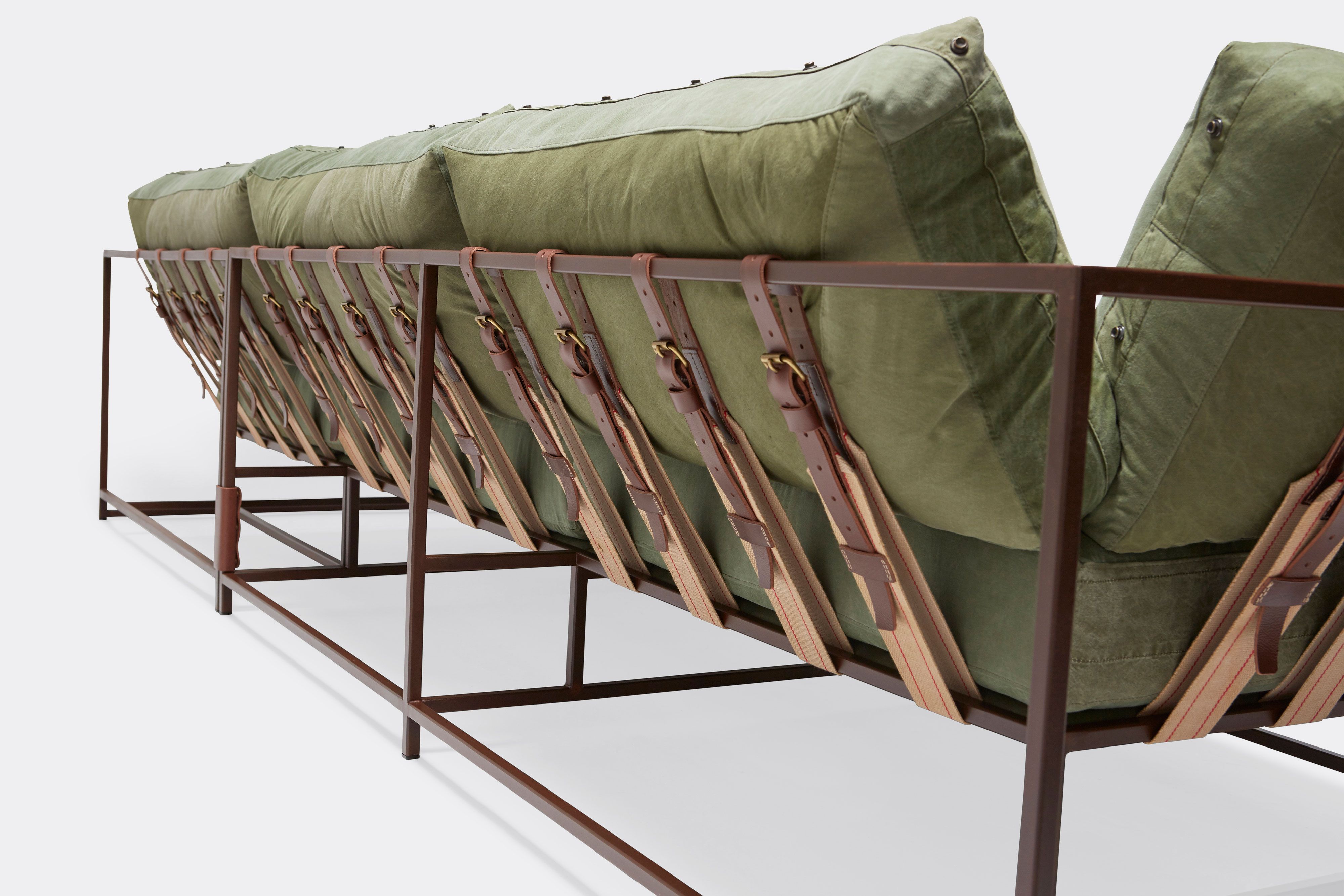 back of sectional with green canvas upholstery and brown leather belts on marble rust metal frame