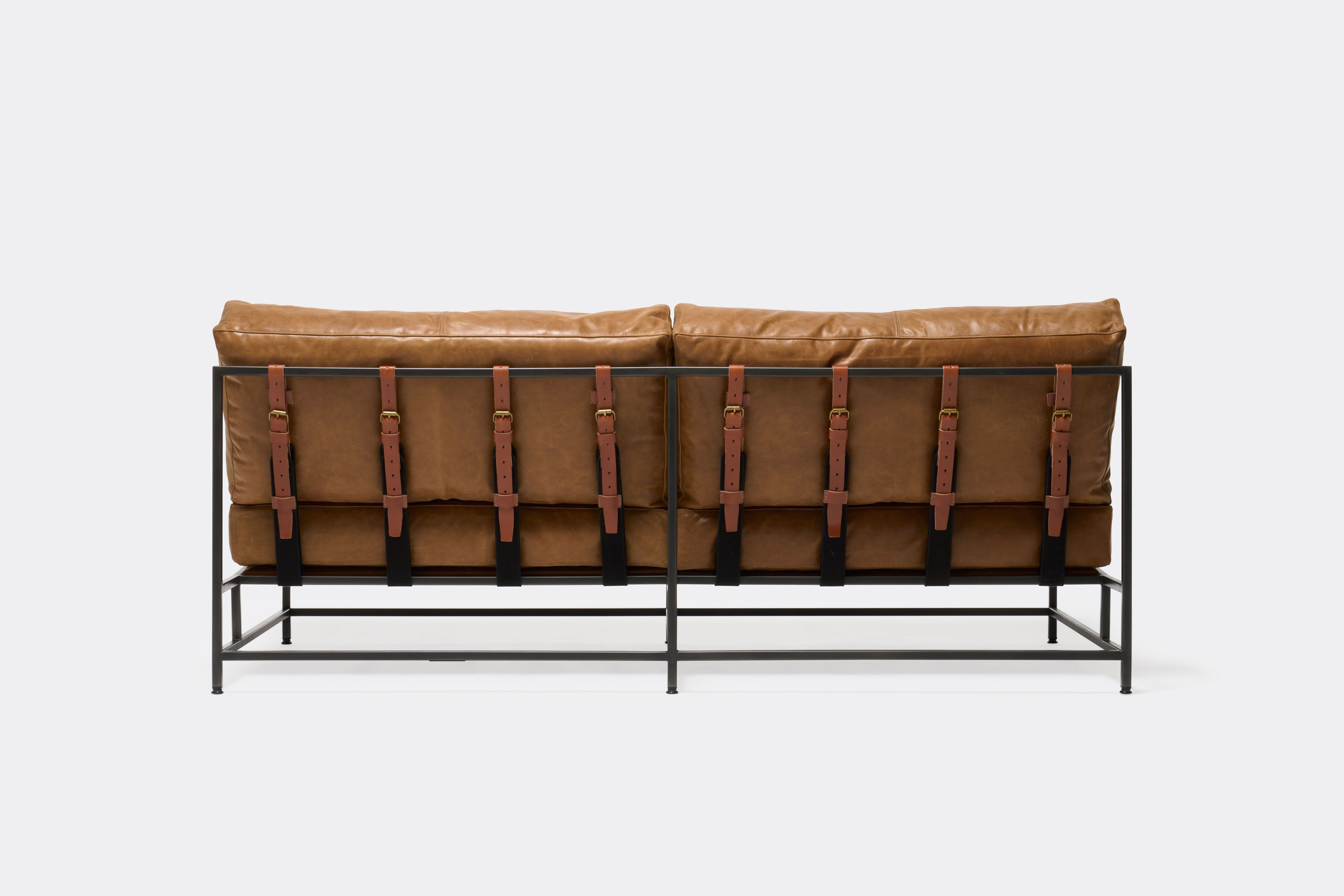 back of loveseat with brown leather upholstery and brown leather belts on black metal frame