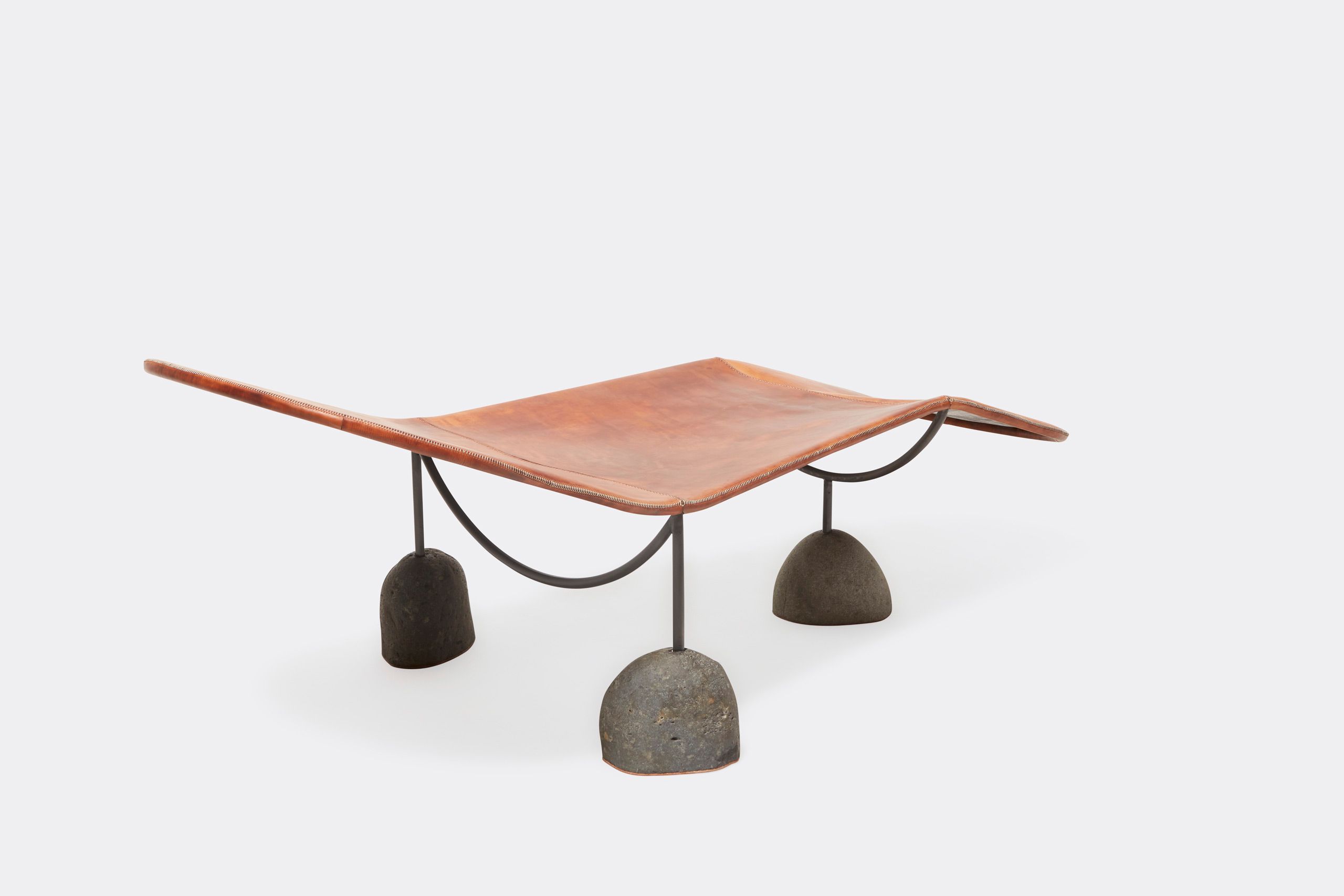 a brown leather chaise lounge with a steel frame and stone base shown on a white background .