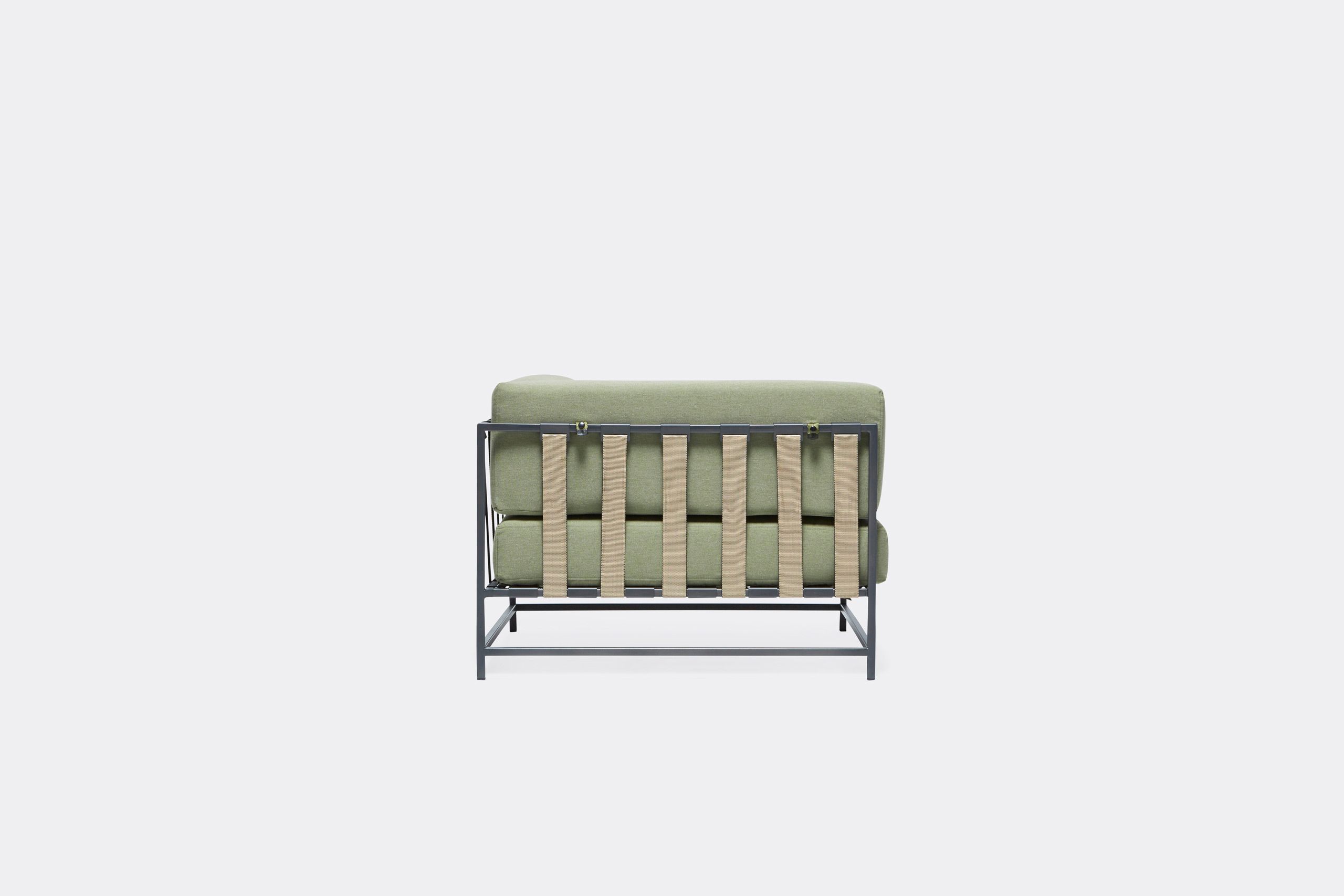 An outdoor chair with steel frame in black finish and green cushions and supporting belts
