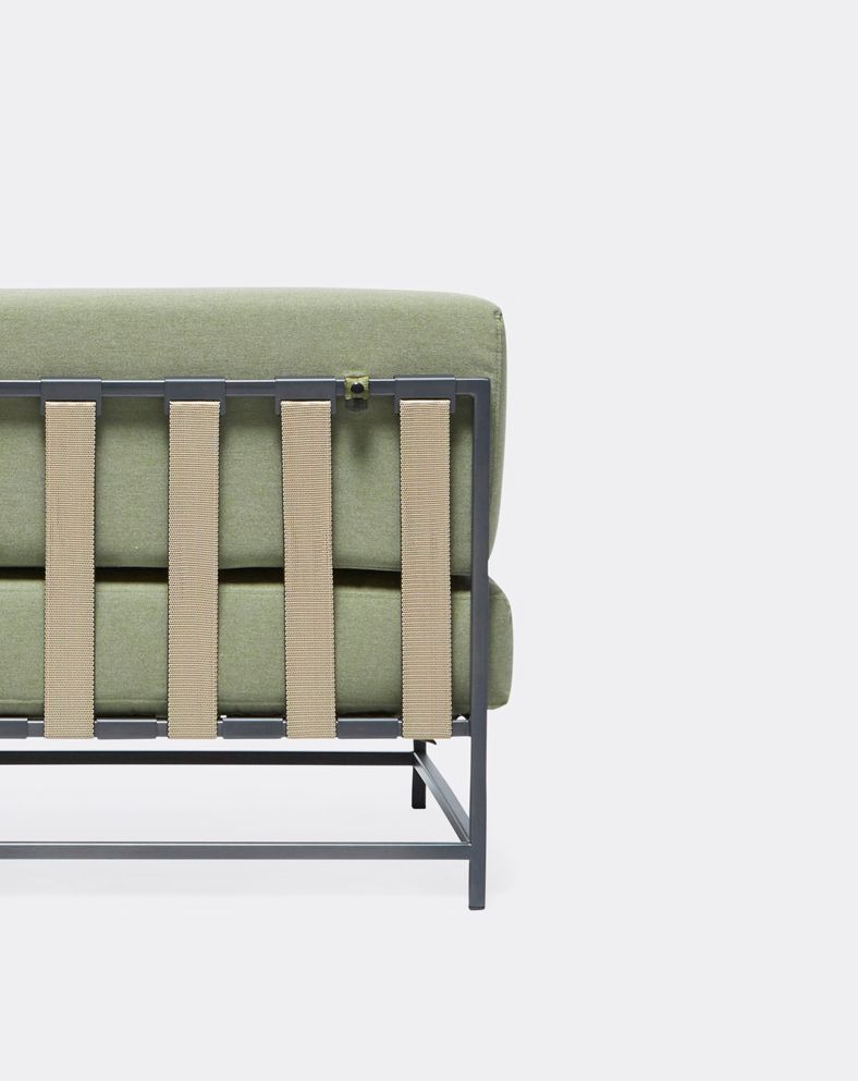 An outdoor chair with steel frame in black finish and green cushions and supporting belts
