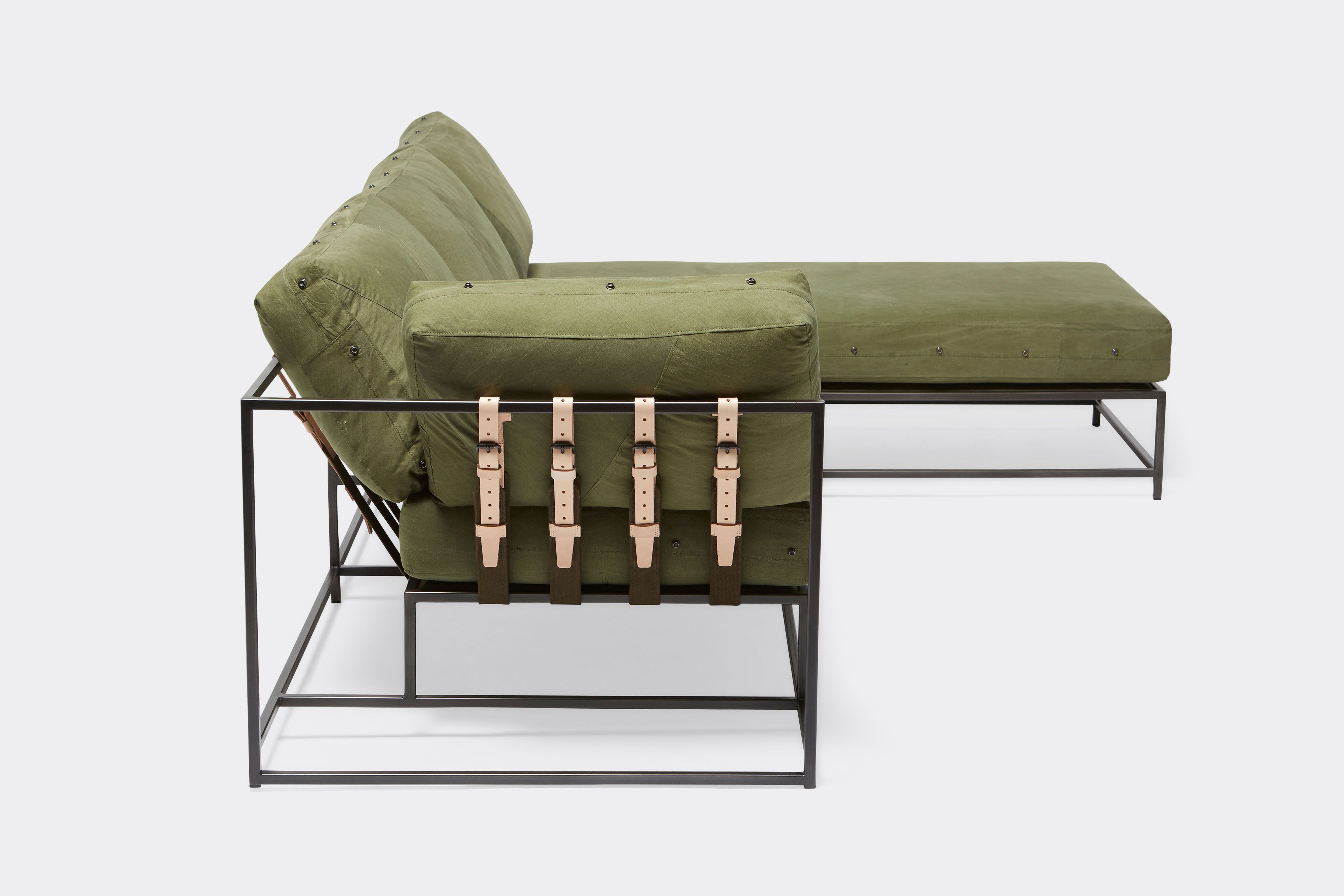 side of sectional with green canvas upholstery and natural tan leather belts on black metal frame