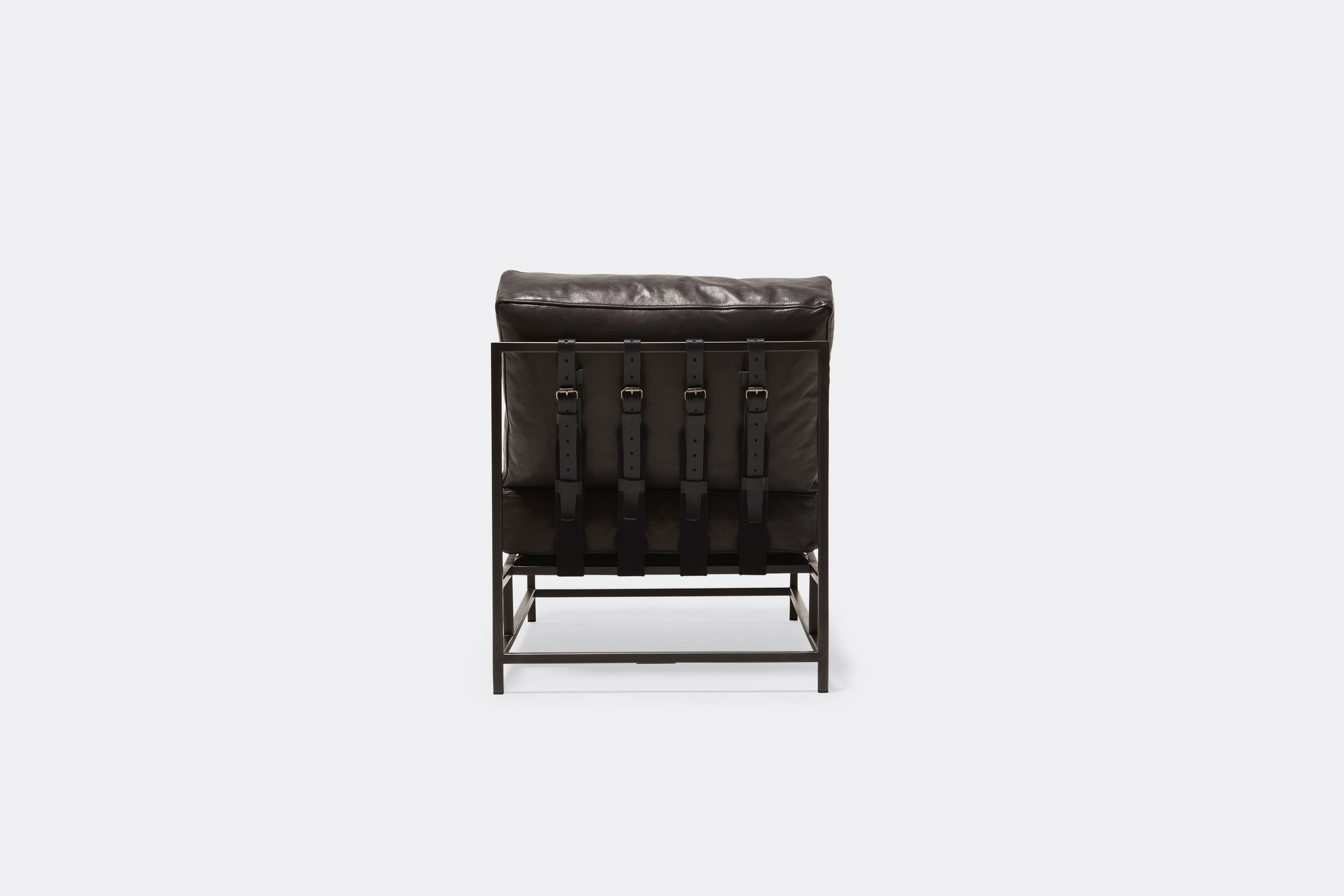 Back of lounge chair with black leather upholstery and black leather belts on black metal frame