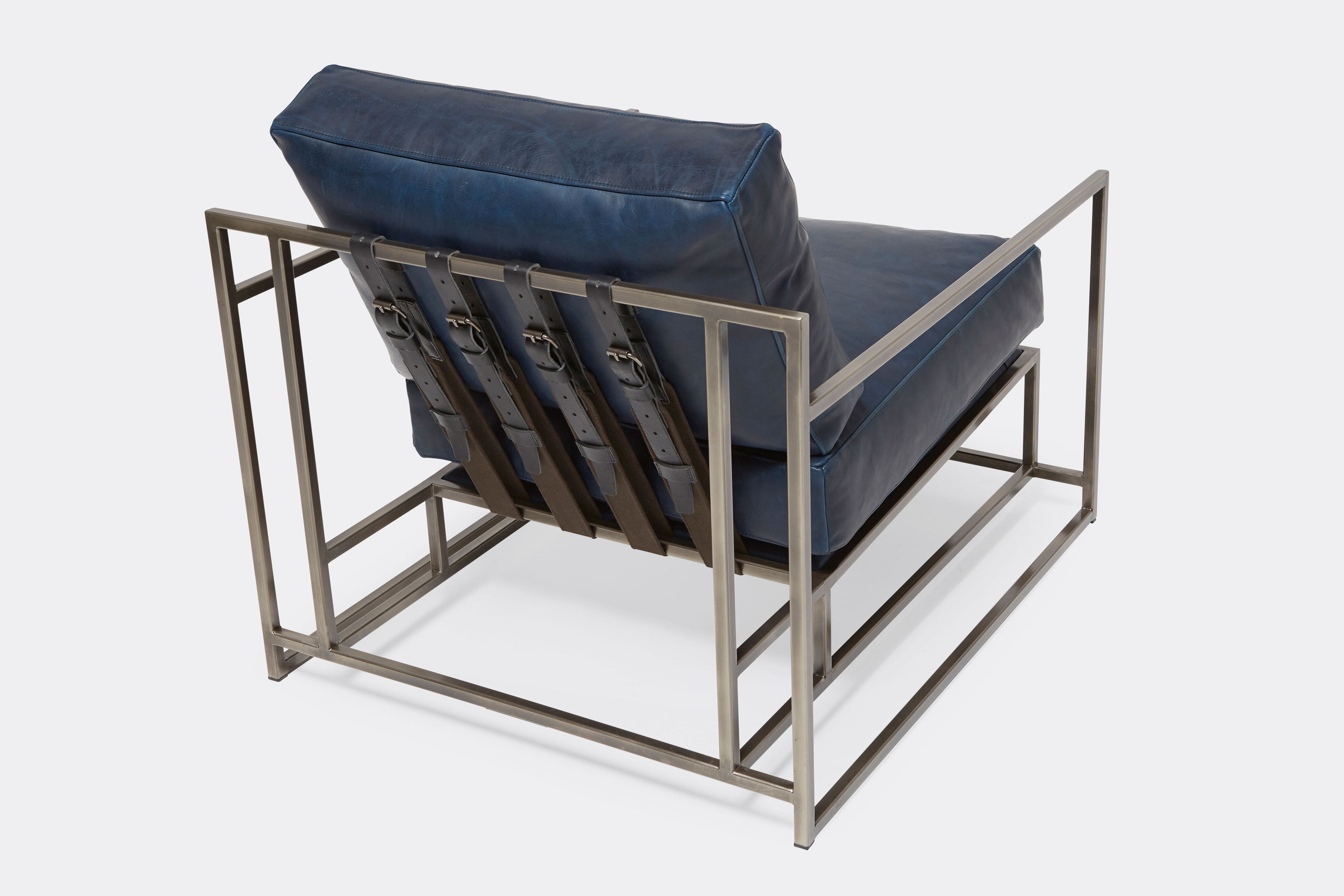 overhead view of armchair with blue leather upholstery and black leather belts on antique nickel metal frame