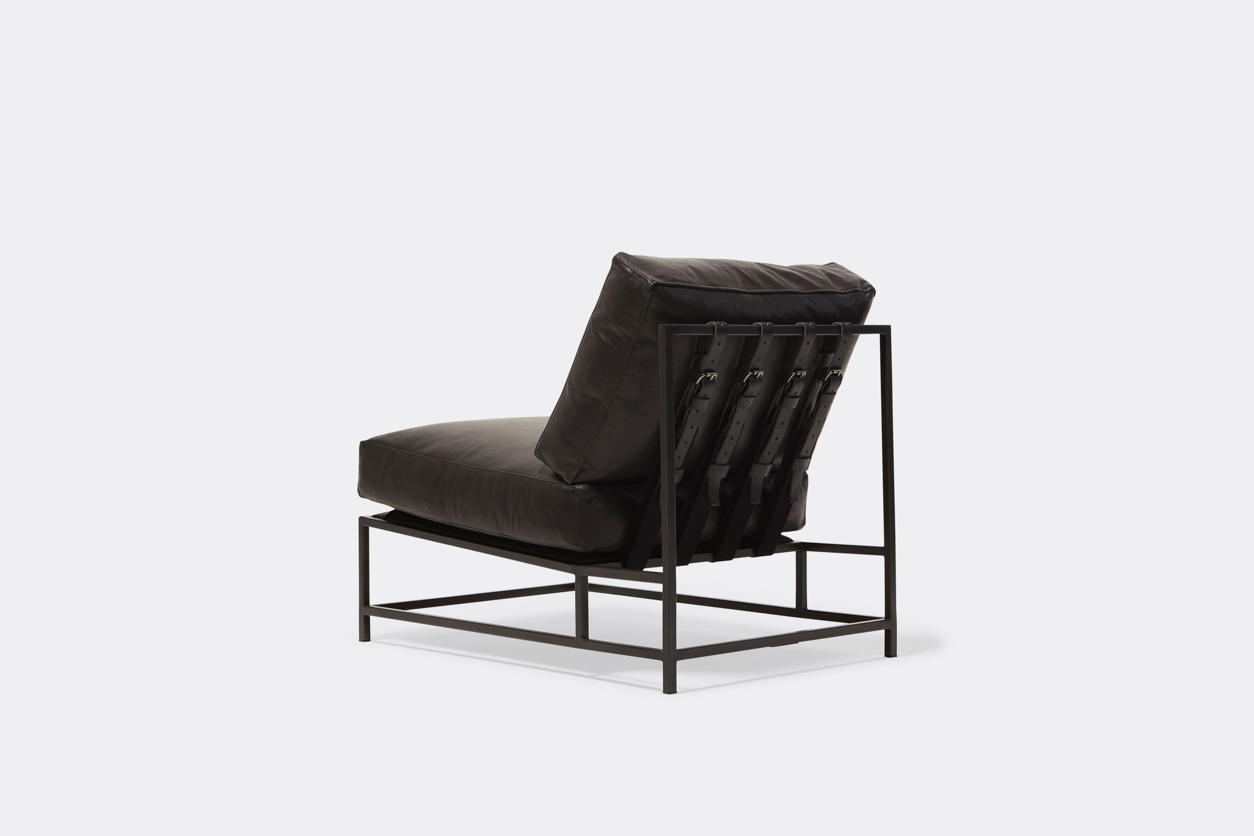 Back of lounge chair with black leather upholstery and black leather belts on black metal frame