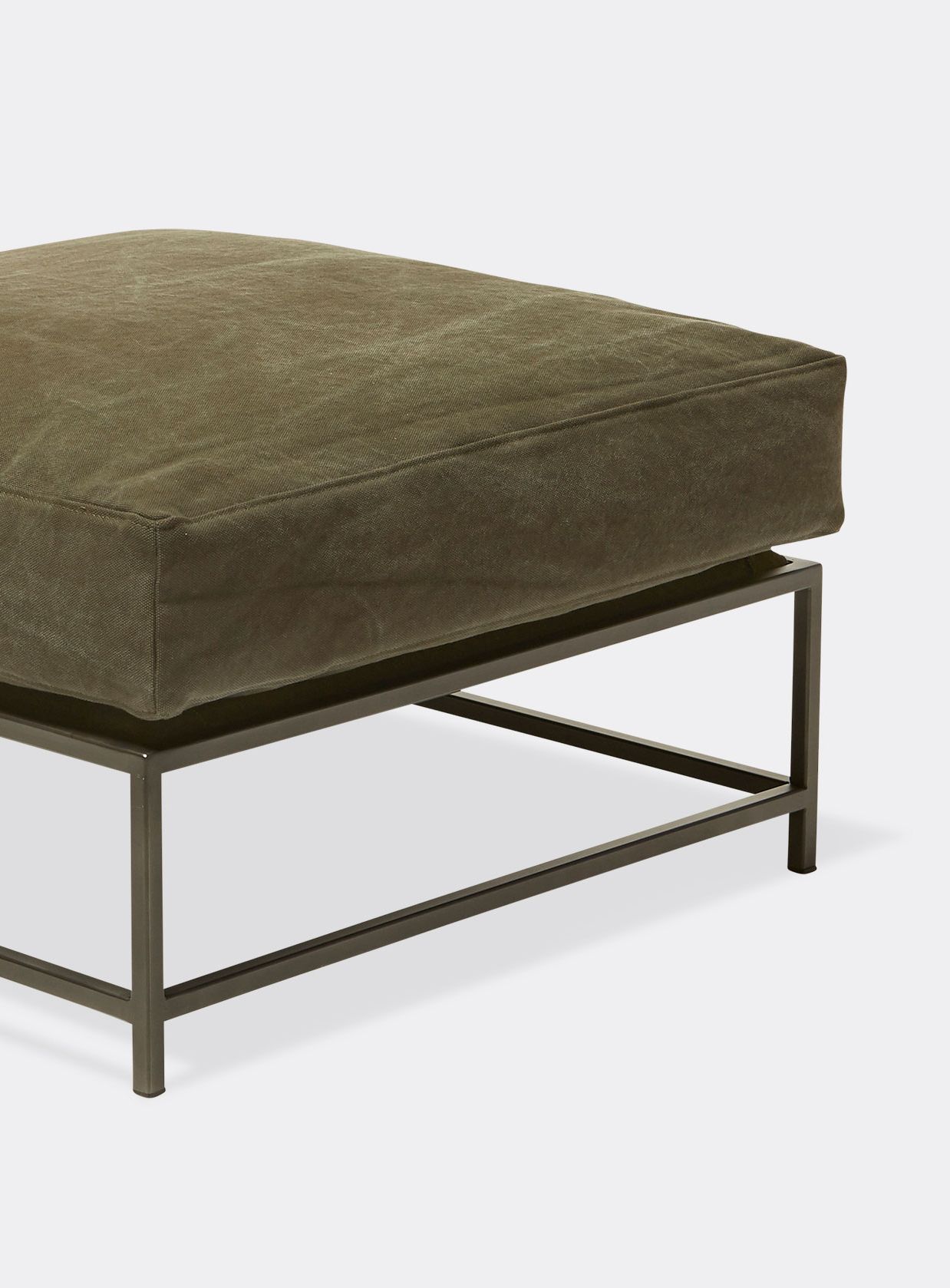 a canvas upholstered ottoman with a metal frame on a white background .
