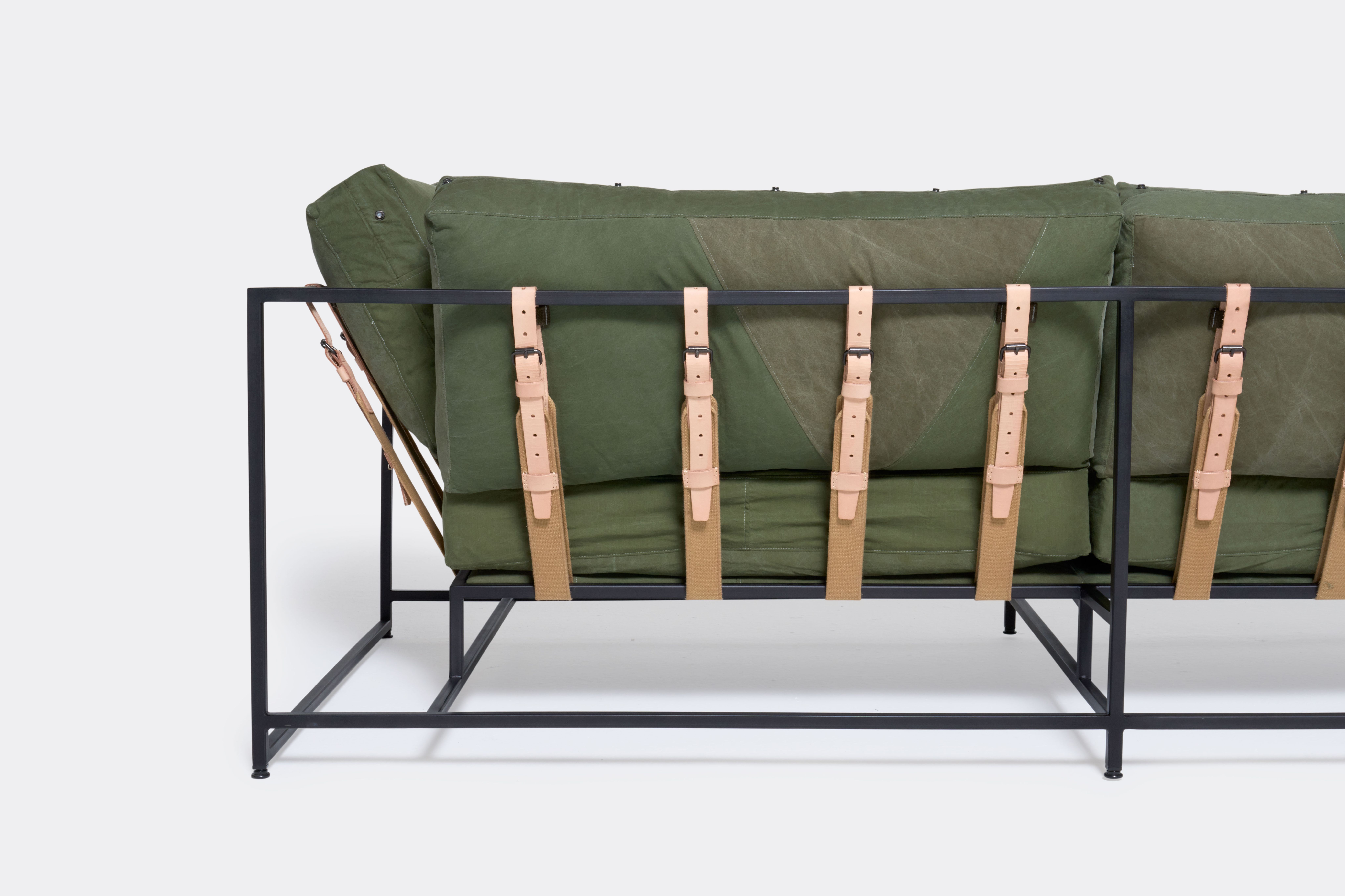 a green sofa with a black steel frame and green cushions on a white background .