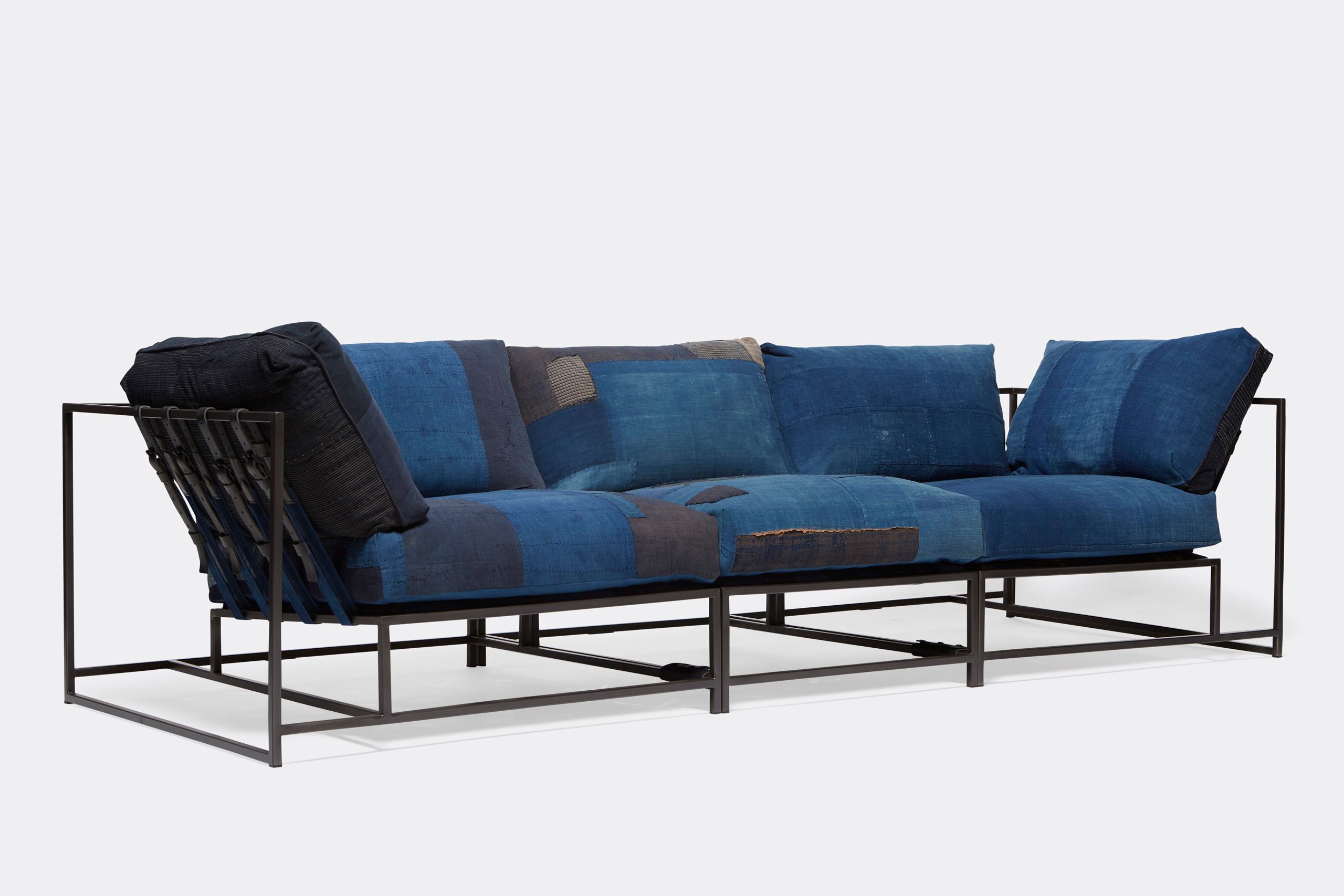 A steel framed sofa with vintage Japanese indigo and grey upholstery and supporting belts shown on a white background