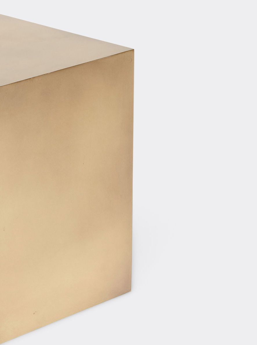 a small brass block table is sitting on a white surface .