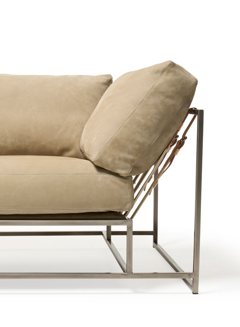 a tan leather couch with a metal frame and supporting belts shown on a white background