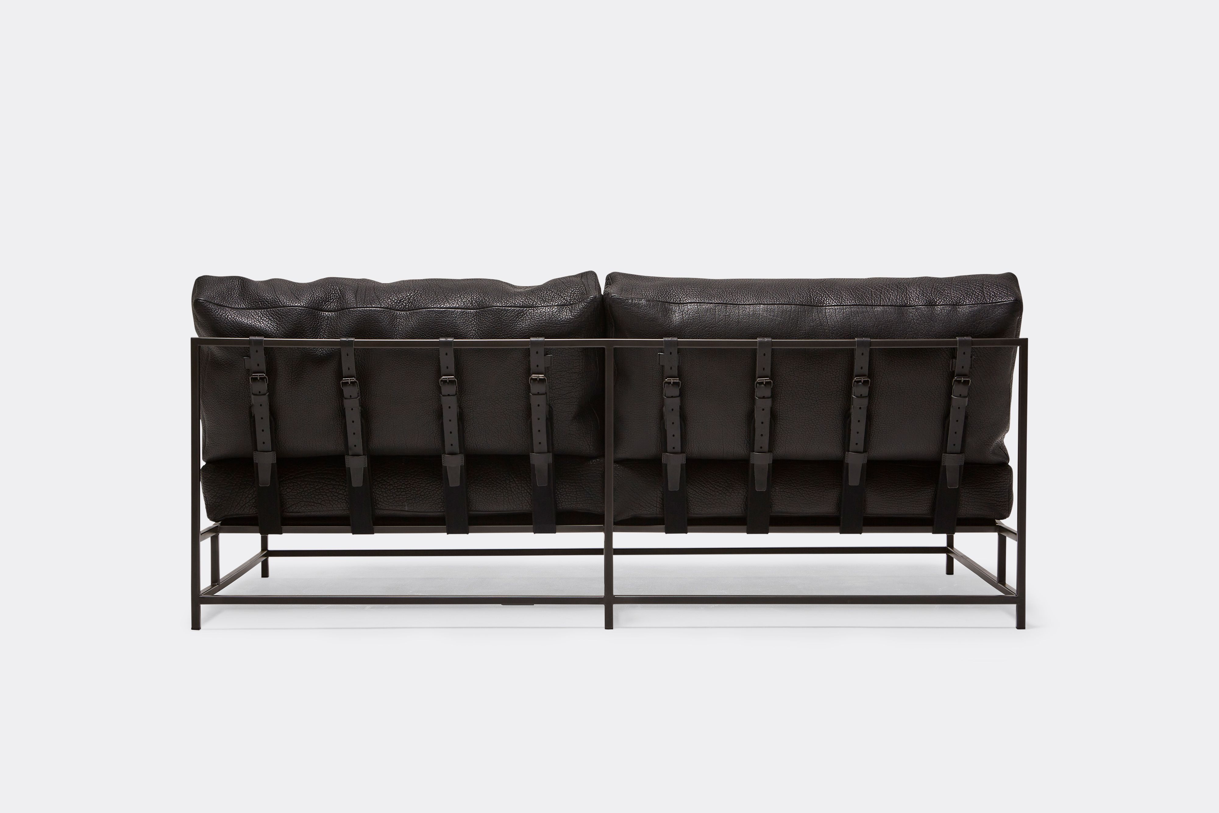 back of loveseat with black leather upholstery on black metal frame