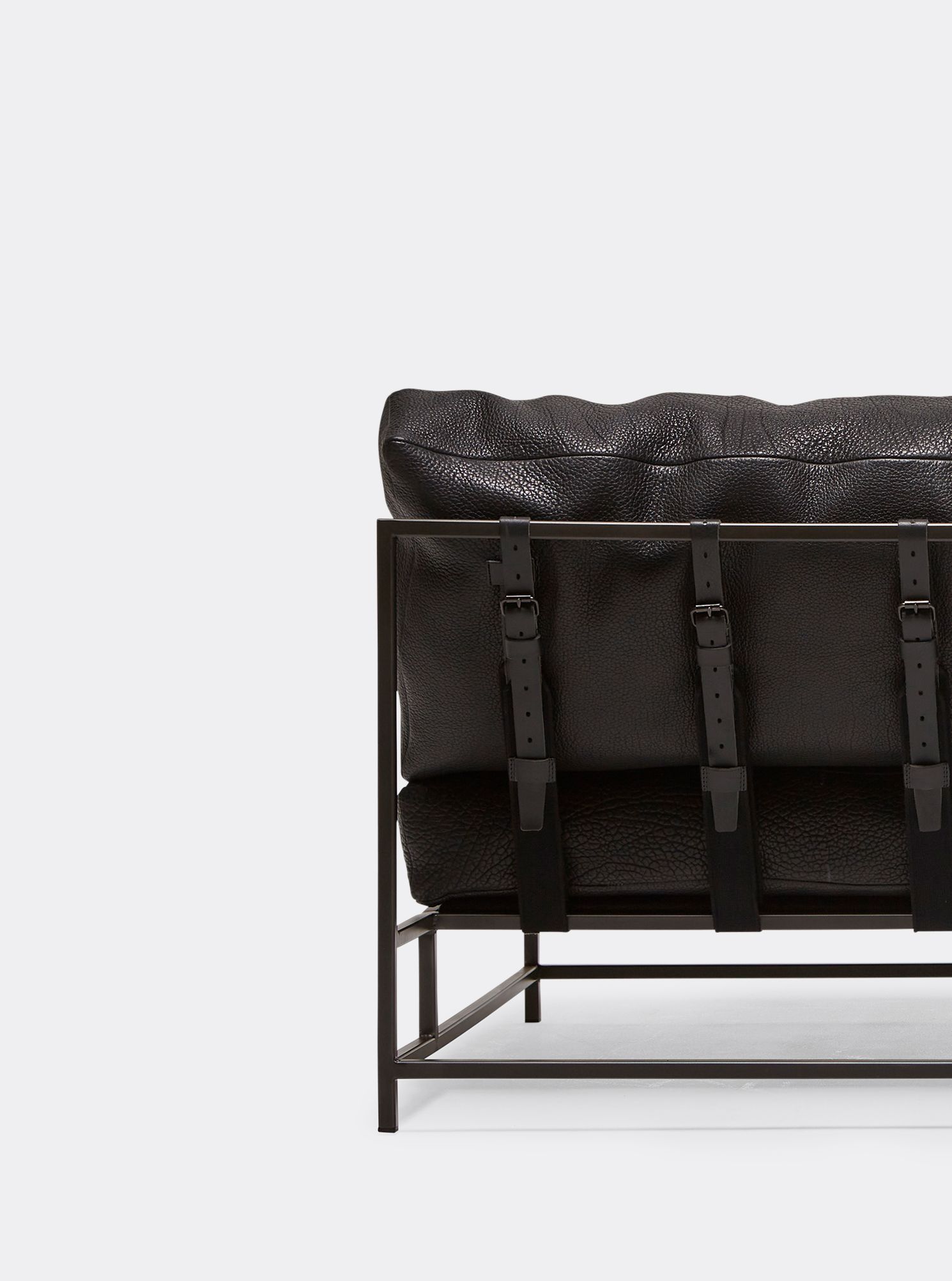 a black leather sofa with a blackened steel frame with black leather and webbing belts shown on a white background .