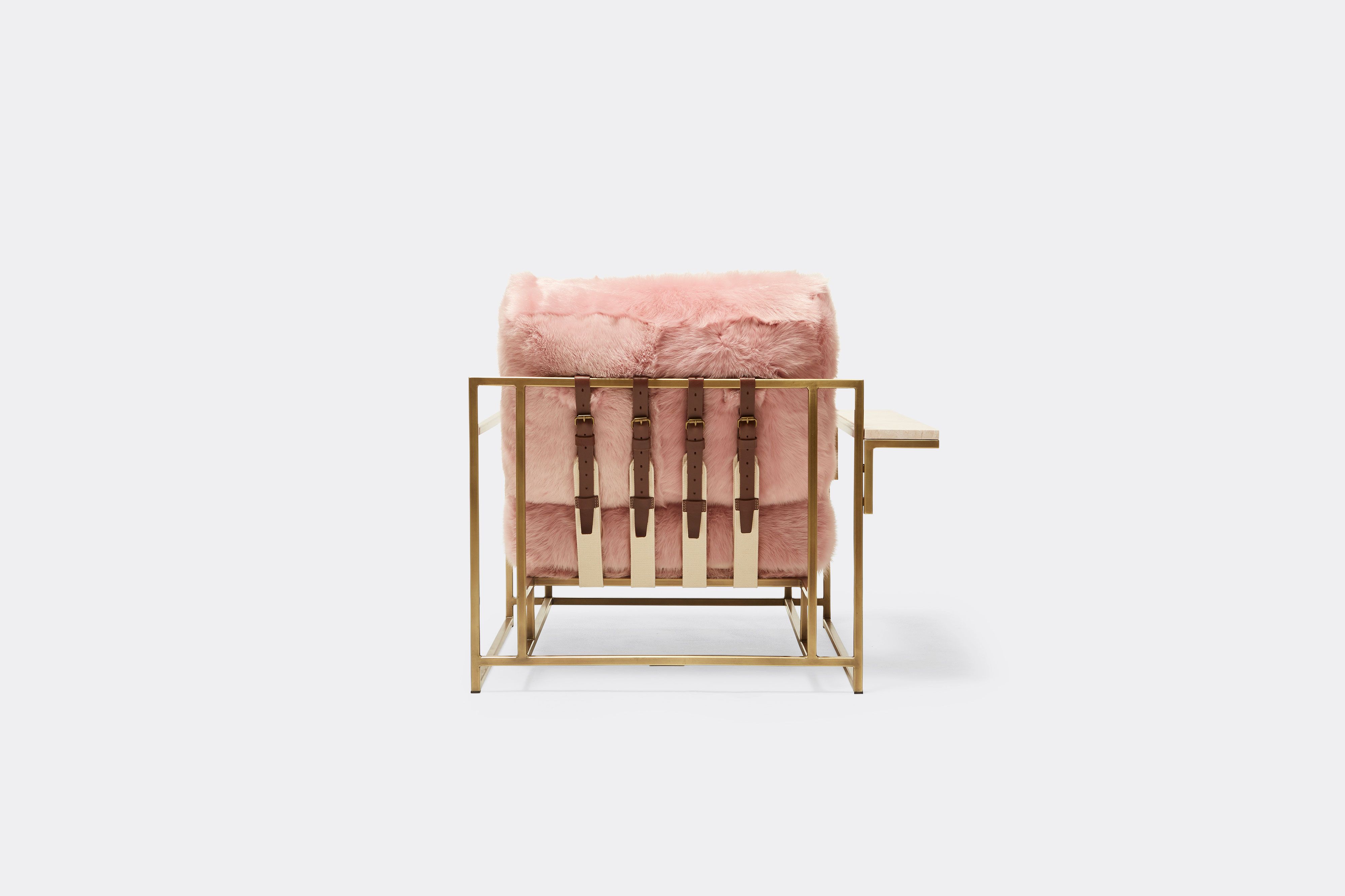 back of armchair with pink shearing upholstery and brown leather belts on antique brass metal frame