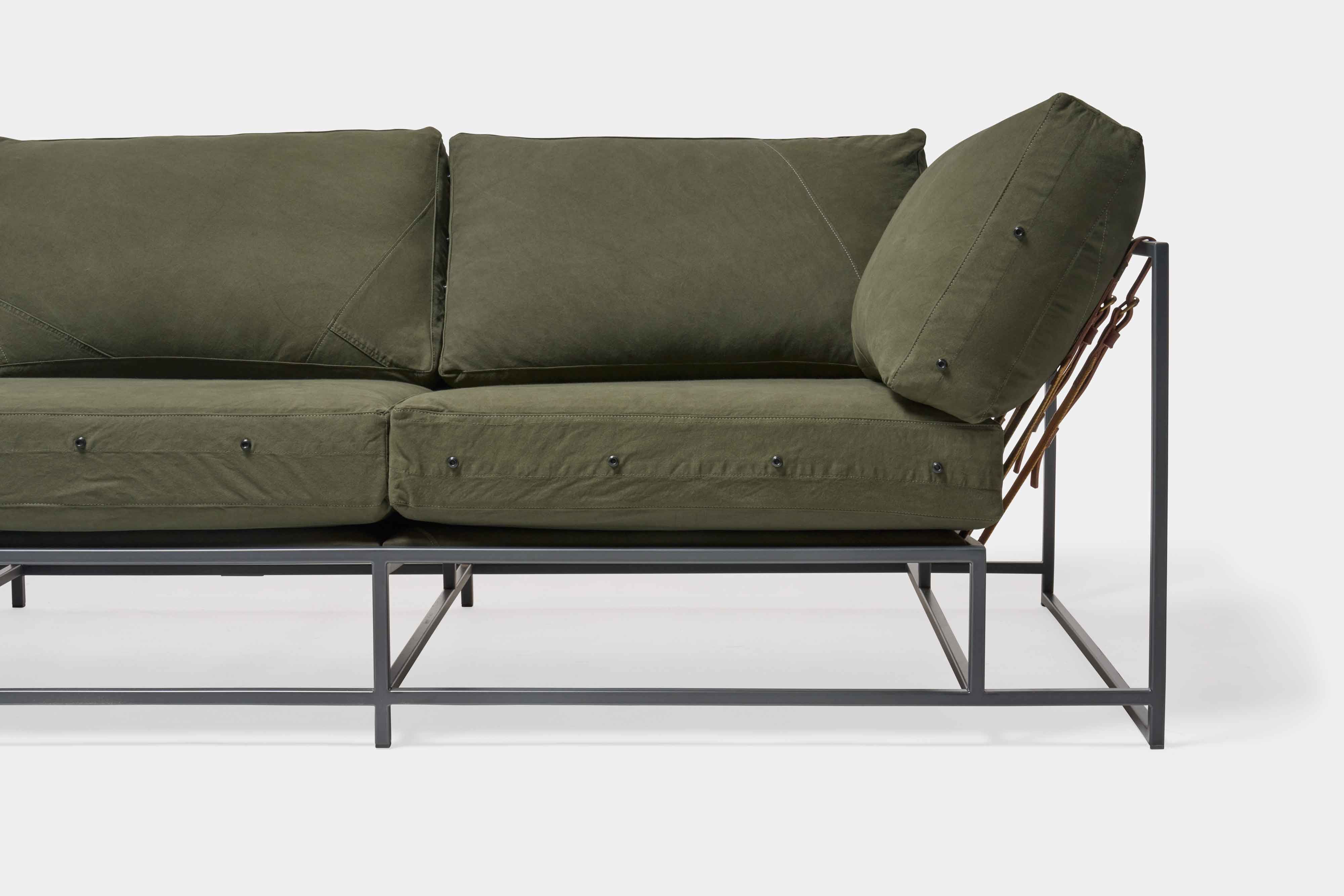 a green couch with a metal frame and leather straps
