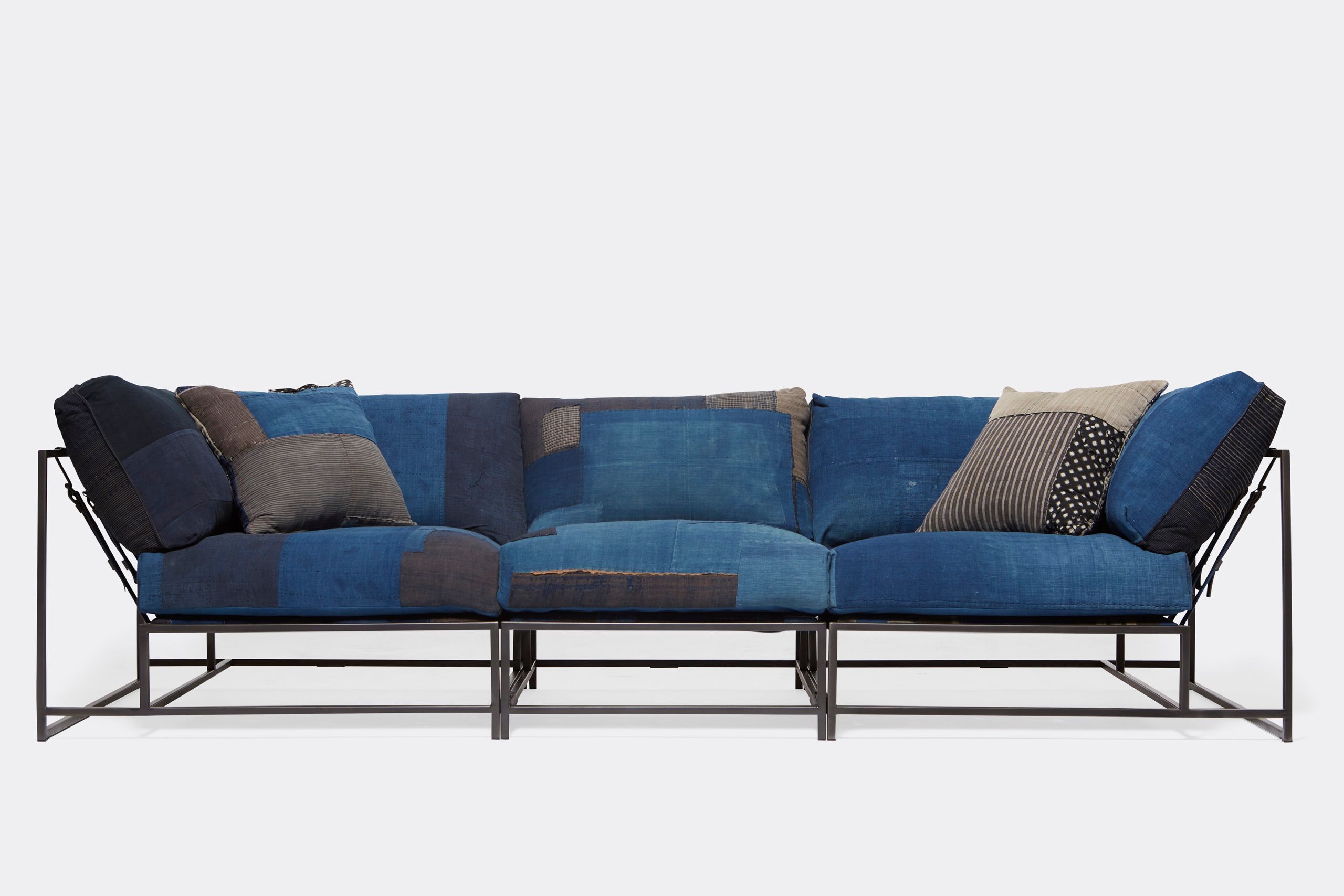 A steel framed sofa with vintage Japanese indigo and grey upholstery and supporting belts shown on a white background