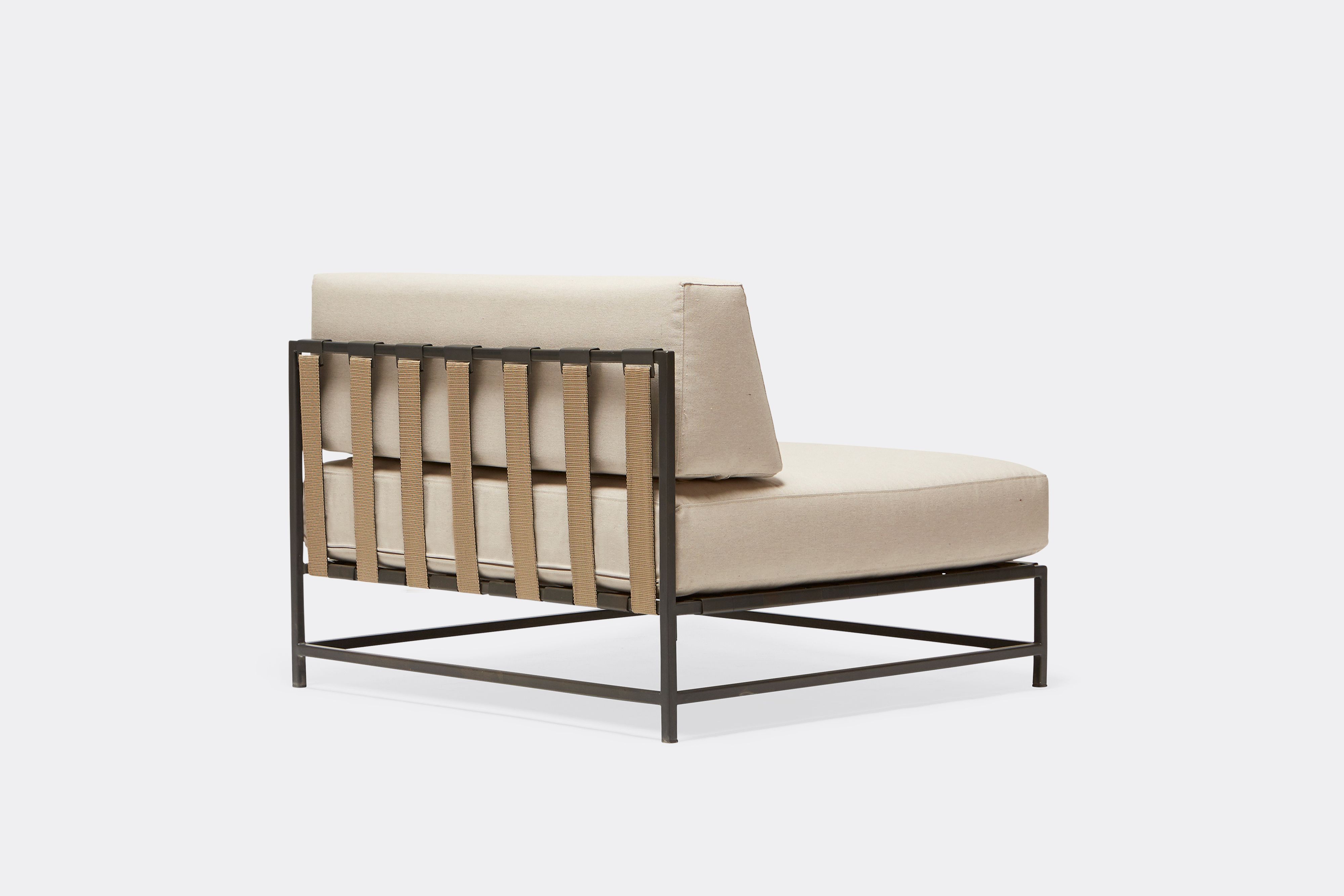 back of outdoor chair with cream canvas upholstery and tan belts on charcoal metal frame