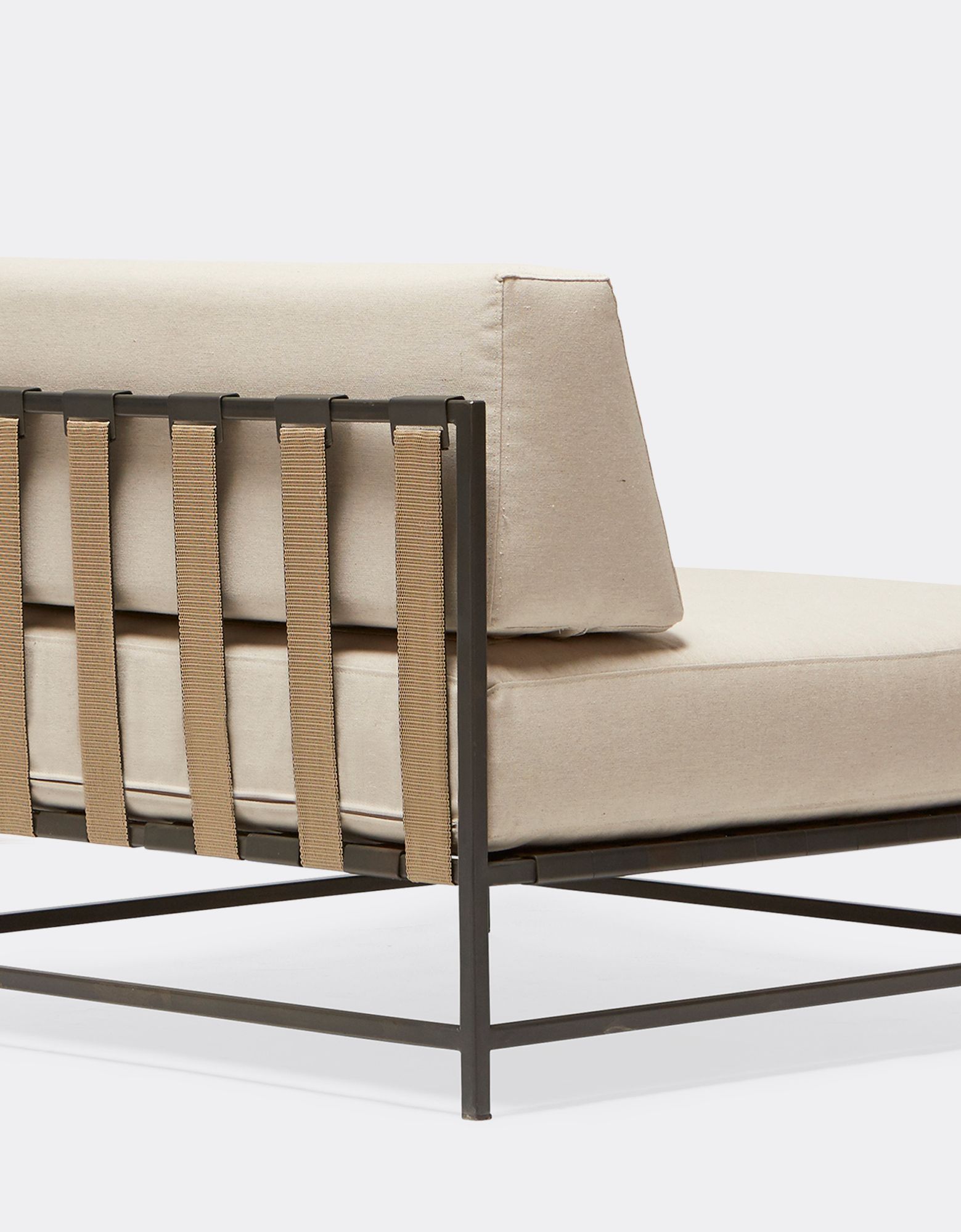 A steel chair with black metal finish and woven tan webbing and a cream cushion on a white background .