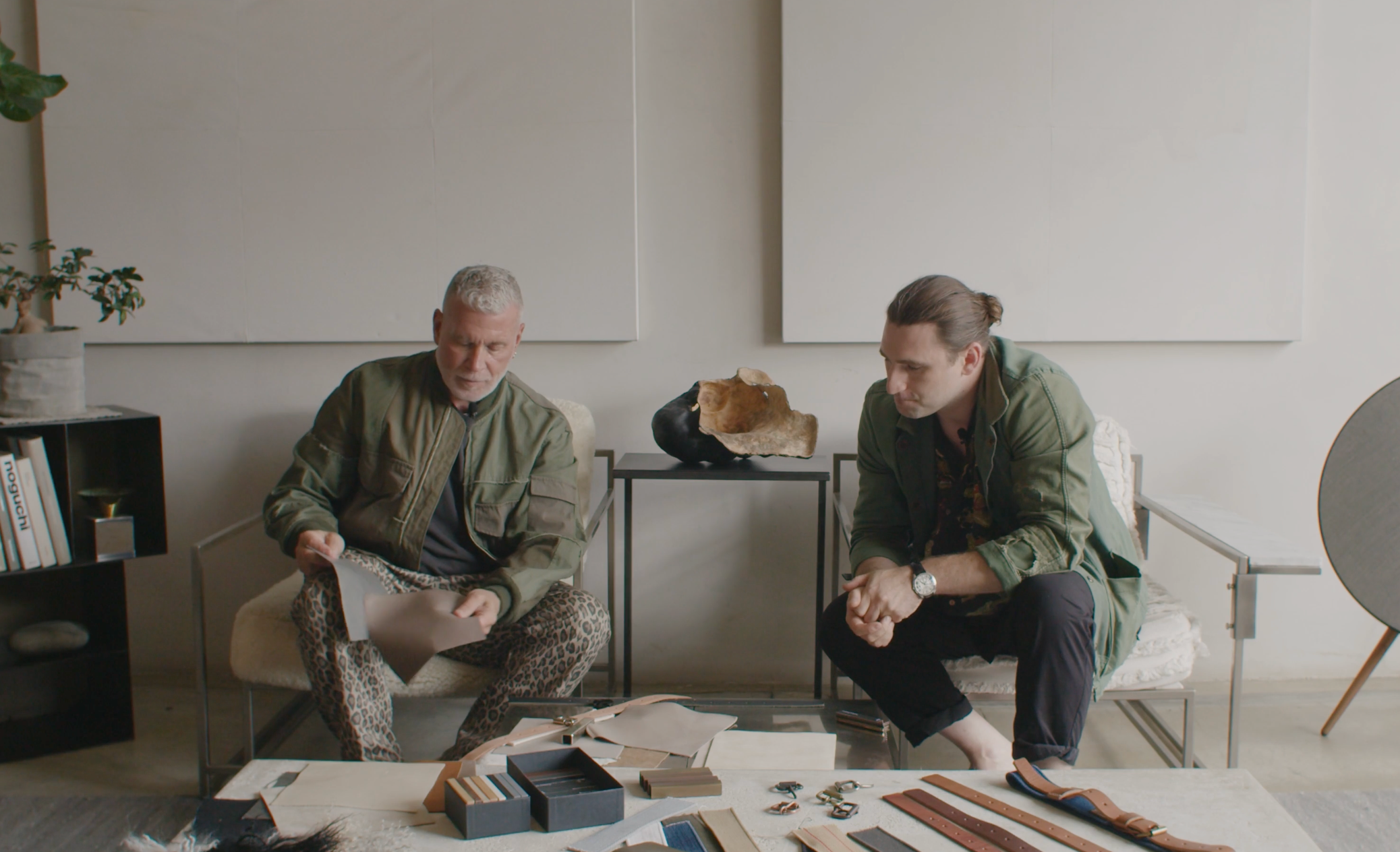 Two men examining design material samples on a coffee table in a modern room.