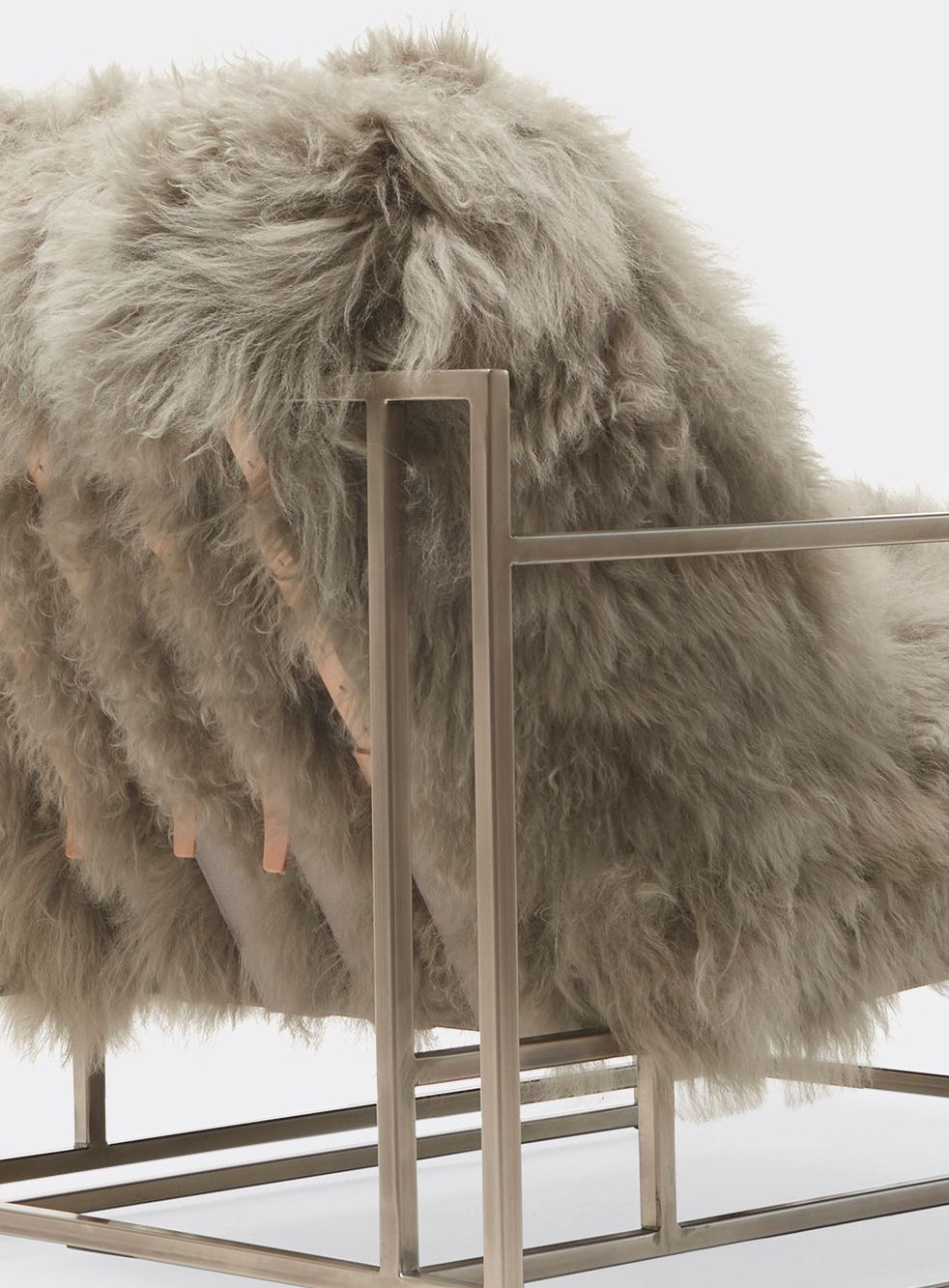 a grey sheepskin armchair with a nickel finished steel frame and leather supporting belts shown on a white background .