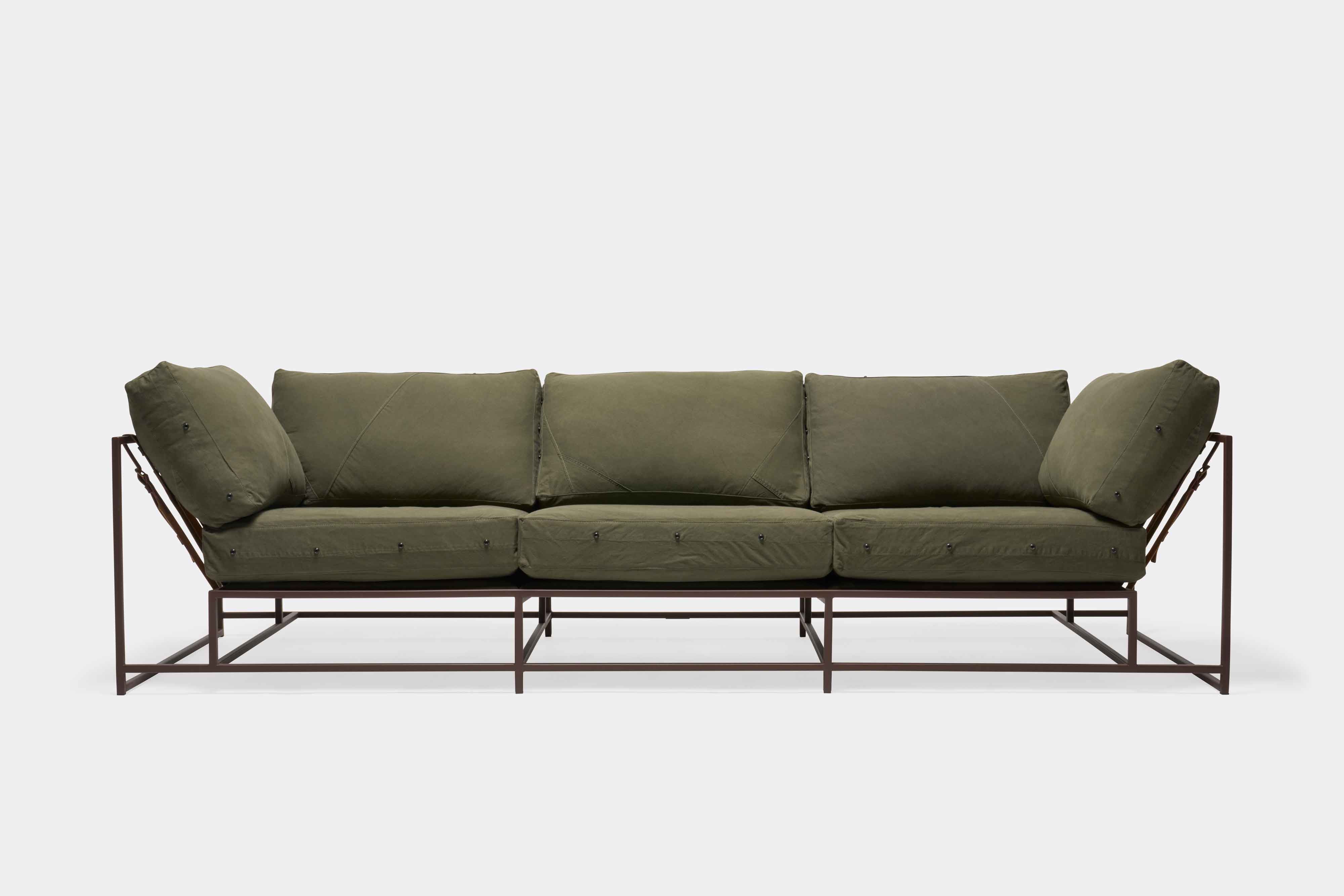 a green couch with a metal frame and leather straps