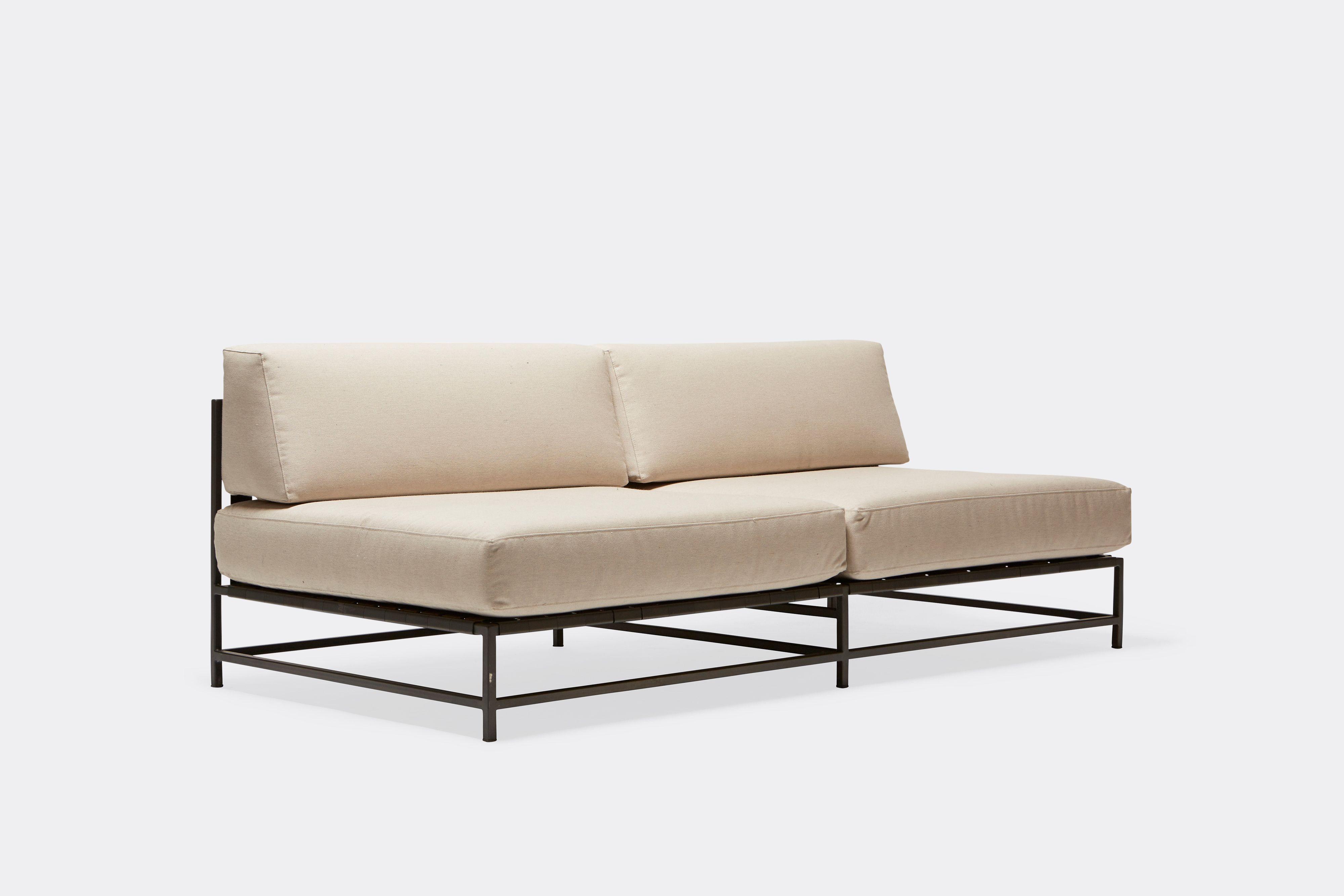 side of outdoor loveseat with cream canvas upholstery on dark grey metal frame