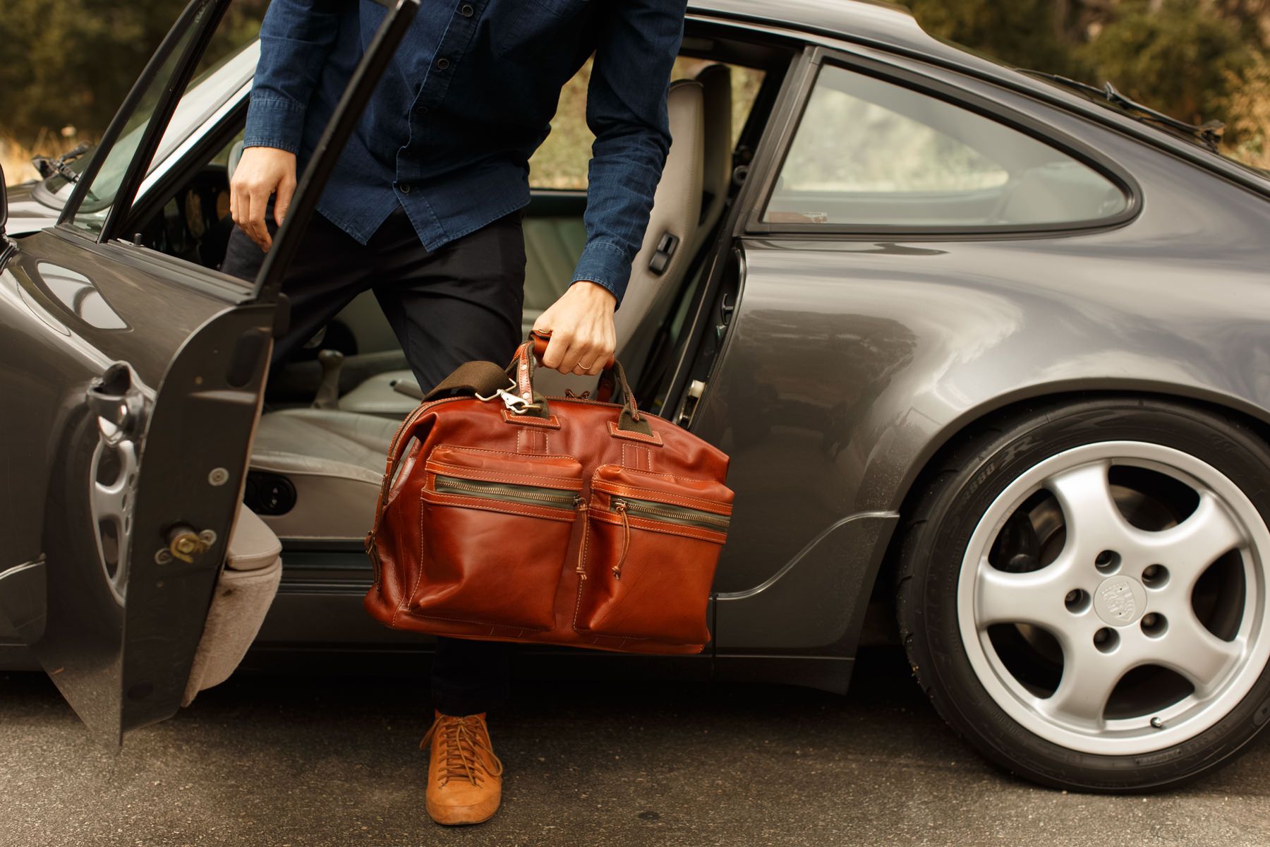 a man is getting out of a car with a bag in his hand .