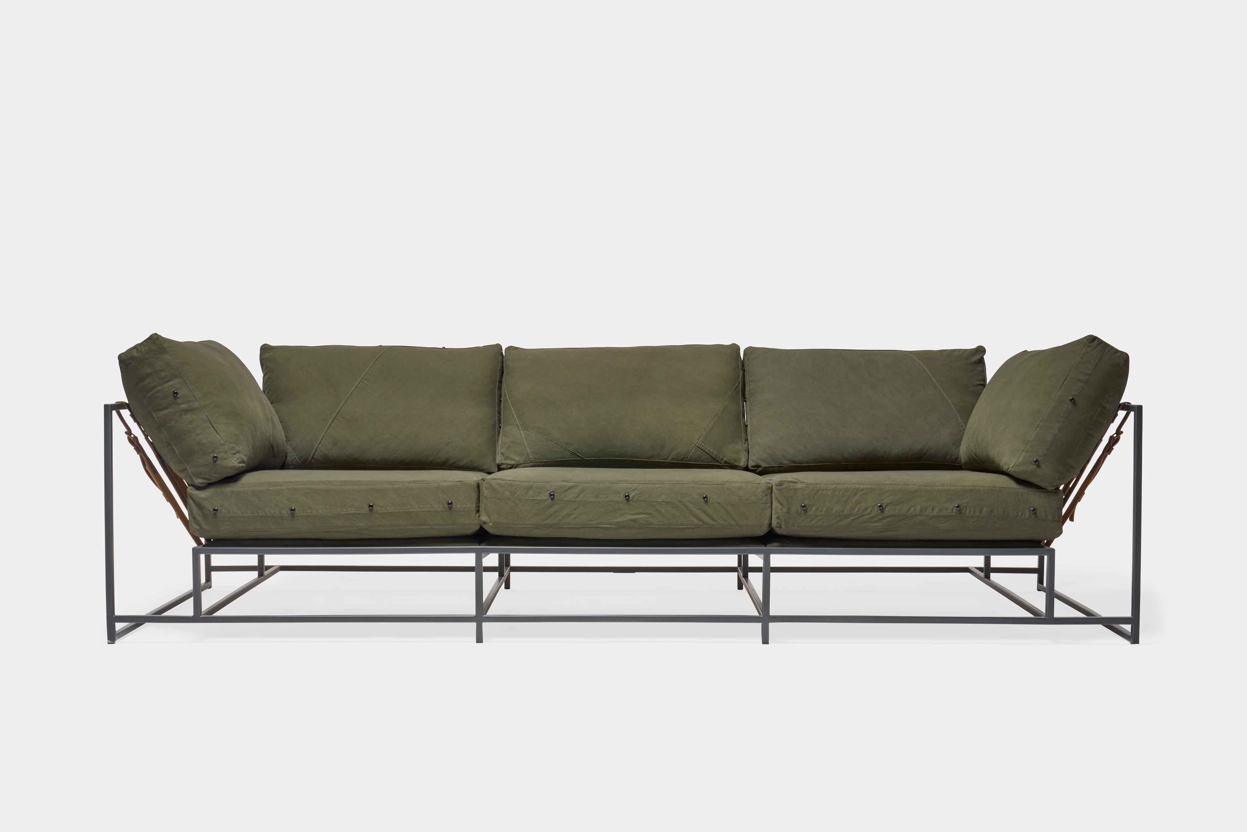 a green couch with a metal frame and leather straps